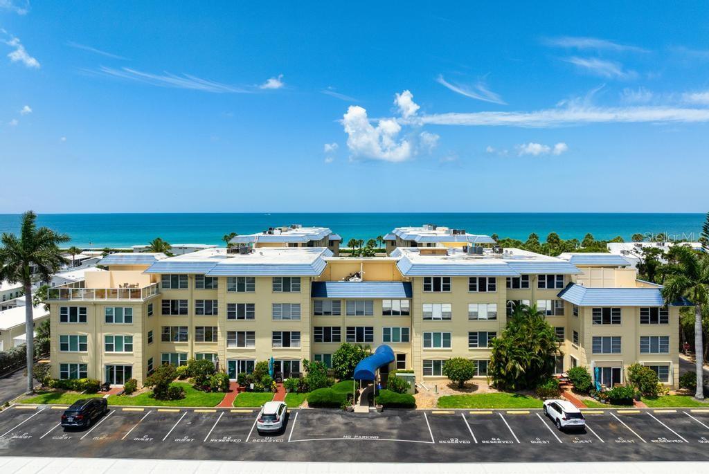 Discover Your Slice of Paradise! This charming turnkey 2-bedroom, 2-bath condo is perfectly positioned between the Gulf of Mexico and Sarasota Bay, offering breathtaking sunrise and sunset views. Enjoy deeded beach access complete with lounge chairs, picnic tables, charcoal grills, and outdoor showers. On the bayside, recent upgrades include a new dock with first-come boat slips, community kayaks, an electric kayak launch, and a fishing pier with a cleaning station. Host a BBQ at the tiki hut or relax by the heated pool featuring gas grills, indoor restrooms, and an outdoor shower. The newly renovated clubhouse offers an upgraded fitness center, card room, large bar, full kitchen, and plenty of gathering space for entertaining.During season, this vibrant and friendly community comes alive with Wednesday night happy hours and festive celebrations including St. Patrick’s Day, Mardi Gras, Cinco de Mayo, and more.