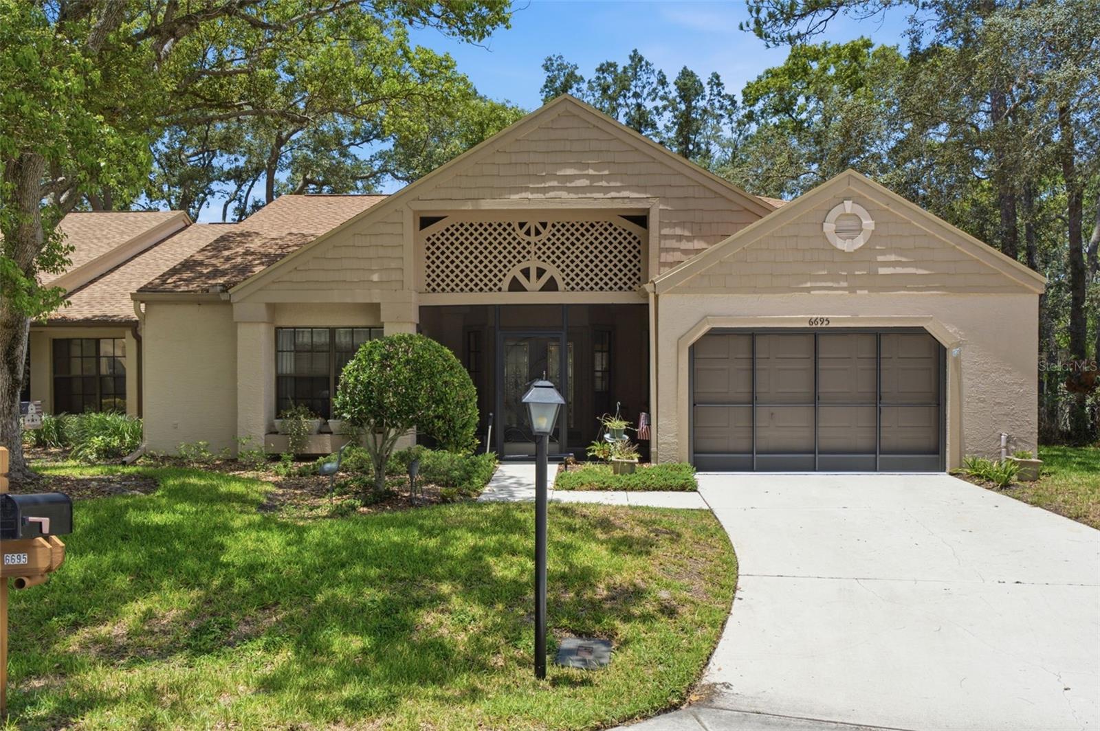 Resort-style 55+ living starts here in Timber Pines! Welcome to 6695 Pin Oak Court, a beautifully maintained villa tucked away on a peaceful cul-de-sac in the gated, pet-friendly community of Timber Pines in Spring Hill. Located in desirable Manor Pines Village, this light and bright 2 bed/2 bath home offers a comfortable split-bedroom layout, flexible living space, and access to a village pool in addition to Timber Pines’ impressive community amenities.

A screened front entry welcomes you inside through leaded glass double doors into a spacious living room filled with natural light. The open flow continues into a versatile enclosed lanai/den under heat and air, perfect for a home office, sitting room, hobby space, or additional entertaining area. Just beyond, enjoy a large outdoor patio with privacy wall, creating a quiet spot for morning coffee, outdoor dining, or grilling with friends.

The kitchen offers newer stainless steel appliances, a pantry, breakfast nook, and pleasant views into the dining area, making everyday living both functional and inviting. The primary suite features generous natural light, engineered hardwood flooring, a large walk-in closet, and an en-suite bath with a step-in shower and built-in bench. The guest bedroom also includes a walk-in closet and is conveniently located near the guest bath with tub/shower combination.

The spacious 1-car-plus garage provides room for storage or a golf cart and includes the laundry area with washer, dryer, utility sink, storage cabinets, pull-down attic access, ceiling fan, and garage screen. Notable updates include a roof replaced in 2023, HVAC handler replaced in 2021, carpeting replaced in 2023, newer hot water heater, newer stainless appliances, and screened entry enclosure added in 2019.

Timber Pines is known for its beautiful park-like setting, active lifestyle, and impressive amenities, including multiple golf courses, two geothermal pools, fitness and wellness facilities, pickleball, tennis, bocce, billiards, shuffleboard, woodworking, arts and crafts, a country club restaurant and bar, performing arts center, activity center, walking trails, and more than 100 clubs and activities. There is even a Paw Park for furry companions. Conveniently located near shopping, dining, medical facilities, and the best of the Nature Coast, this home offers low-maintenance living in one of Spring Hill’s most desirable active adult communities.