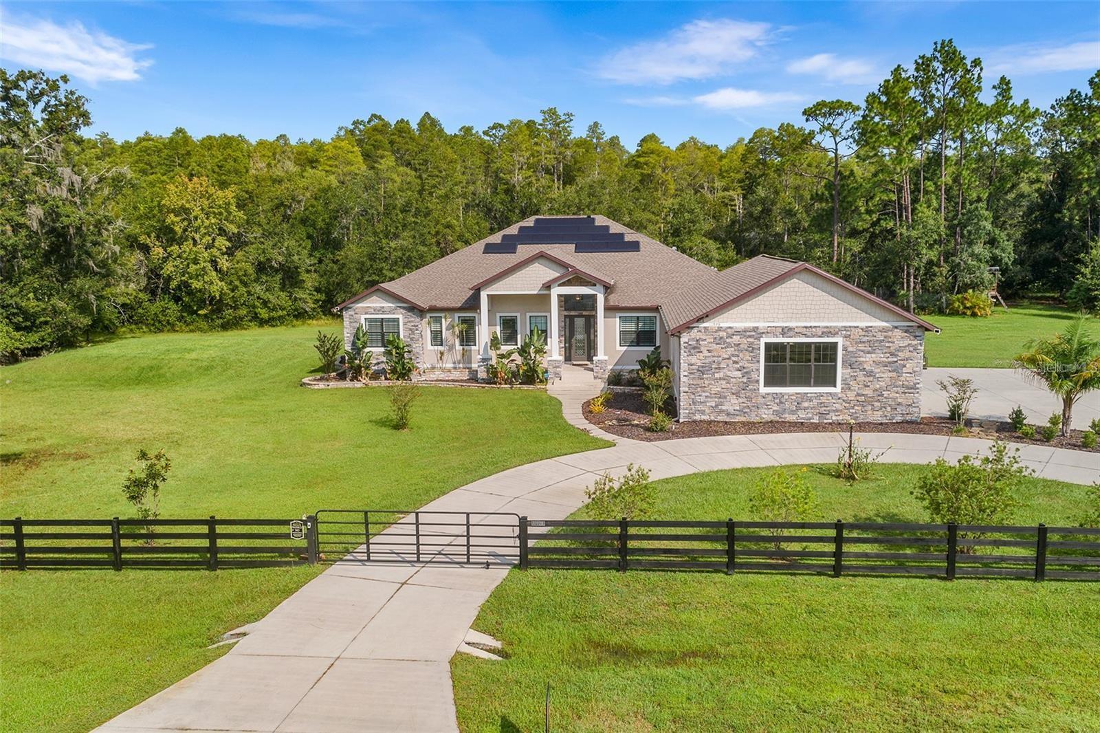One or more photo(s) has been virtually staged. UPDATED PRICE BASED ON RECENT APPRAISAL. Nestled on 13 acres in the exclusive Pasco Trails community, this stunning custom-built home offers luxurious living in a serene setting. Enter through a gated entrance and follow the circle driveway to discover an open floor plan that seamlessly connects the spacious living area, formal dining room, and an oversized gourmet kitchen equipped with commercial stainless steel appliances. The living space flows effortlessly to a sprawling paver patio designed for entertaining, complete with a pool and spa. The master suite is a private retreat, featuring a massive walk-in closet, a cozy sitting area, and direct access to the patio. The en suite bath boasts dual vanities and an oversized walk-in shower. The home also includes four additional bedrooms, a dedicated office, and a versatile bonus room that can serve as a sixth guest bedroom. With 3.5 baths, including a pool bath with direct access to the pool deck, this home is perfect for both relaxation and entertaining. Outside, you'll find a spacious four-car garage with a private workspace and fully fenced front and back yards. Additional features include a whole-home water softener, a comprehensive water filtration system, and a TESLA-powered solar system including three powerwalls for enhanced energy efficiency and peace of mind. Enjoy the tranquility of rural living while being just minutes away from schools, dining, retail, and shopping.