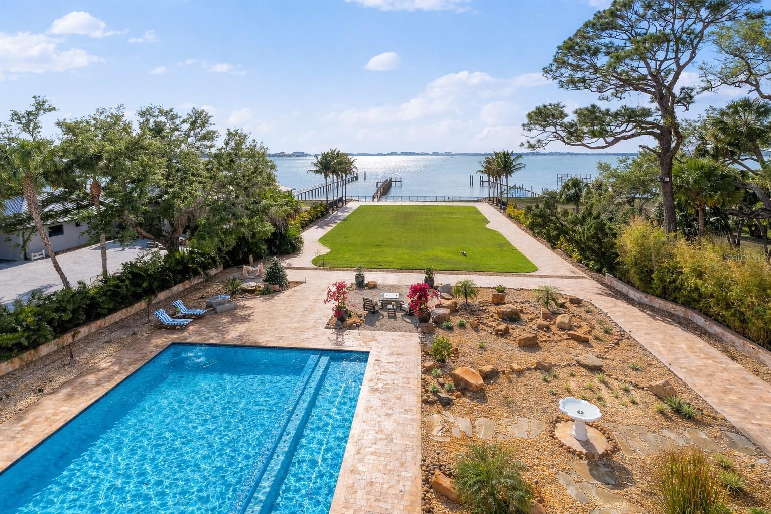 Palazzo Sul Mare is a rare waterfront estate in St. Petersburg’s coveted Jungle Prada neighborhood, offering over 19,000 square feet under roof and more than 10,000 square feet of interior living space on over 1.5 acres along the Intracoastal Waterway. Built in 2020, this residence blends modern construction with timeless European-inspired design—an offering rarely found in this market.
A grand motor court and porte-cochère create a secure, estate-style arrival. An imported limestone exterior, along with wrought iron detailing, a distinctive blue dome, fountain, marble statuary, and mature oak trees, establishes a timeless setting surrounded by tropical landscaping and the neighborhood’s iconic peacocks. Inside, a dramatic domed rotunda crowned by a crystal chandelier anchors the home, featuring inlaid marble flooring and dual sweeping marble staircases. The layout captures water views throughout, with a gallery-style corridor ideal for art, a grand piano, or entertaining. Marble archways and columns, gold and iron balustrades, and detailed ceilings create a striking architectural presence, while illuminated art niches enhance the home’s scale and design continuity.
Custom millwork, fresco-style ceilings, and imported marble flooring span all three levels. The kitchen features a full suite of Thermador appliances, including a 60-inch gas range, integrated refrigeration, and built-in coffee system, along with quartzite surfaces and an illuminated onyx island. A custom Chihuly-style installation of hand-blown glass creates a focal point above, while the curved glass dining area frames panoramic water and pool views with space for large-scale entertaining.
The residence includes multiple bedroom suites, several exceeding 1,000 square feet, many with spa baths, expansive closets, and private lanais with water or garden views. The main-level primary suite offers a marble bath with Phylrich fixtures, sauna, soaking tub, multiple vanities, and panoramic water views beneath a custom fresco ceiling.
A private office on the main level features paneled walls, built-ins, an ornate stone fireplace, and balcony access. The upper level includes a club-style lounge with a quartzite waterfall bar and sunset views. The home spans three levels with elevator access and marble staircases, with laundry rooms on multiple levels.
Outdoor living includes a zero-entry pool, lap pool, 2 spas (hot and possible cold), 5 terraces, courtyards, fire pit, private sandy beach, citrus trees, and a wide rear lawn. The grounds offer flexibility for a guest house or ADU, sport court, cabana, or greenhouse. The private dock includes a 10,000-lb lift, additional lifts for personal watercraft, a wet slip for a yacht, and direct Gulf access.
Built for longevity with reinforced pier-and-beam construction on pilings, impact-rated windows and doors, and a stone exterior. Designed with engineered elevation, the residence features elevated living areas (approx. 7.7’ first level and 20’+ upper levels), with no reported water intrusion. Smart home technology, full security camera coverage, solar power, saving thousands per month in electricity, 4 HVAC systems (2023) with 10-year warranties, and 2 whole-house generators for efficiency and reliability.
Garage capacity for approximately 6 vehicles includes additional space for a workshop, recreation, or gym with over 5,000 square feet of lower-level space. A rare combination of scale, craftsmanship, and waterfront presence.
