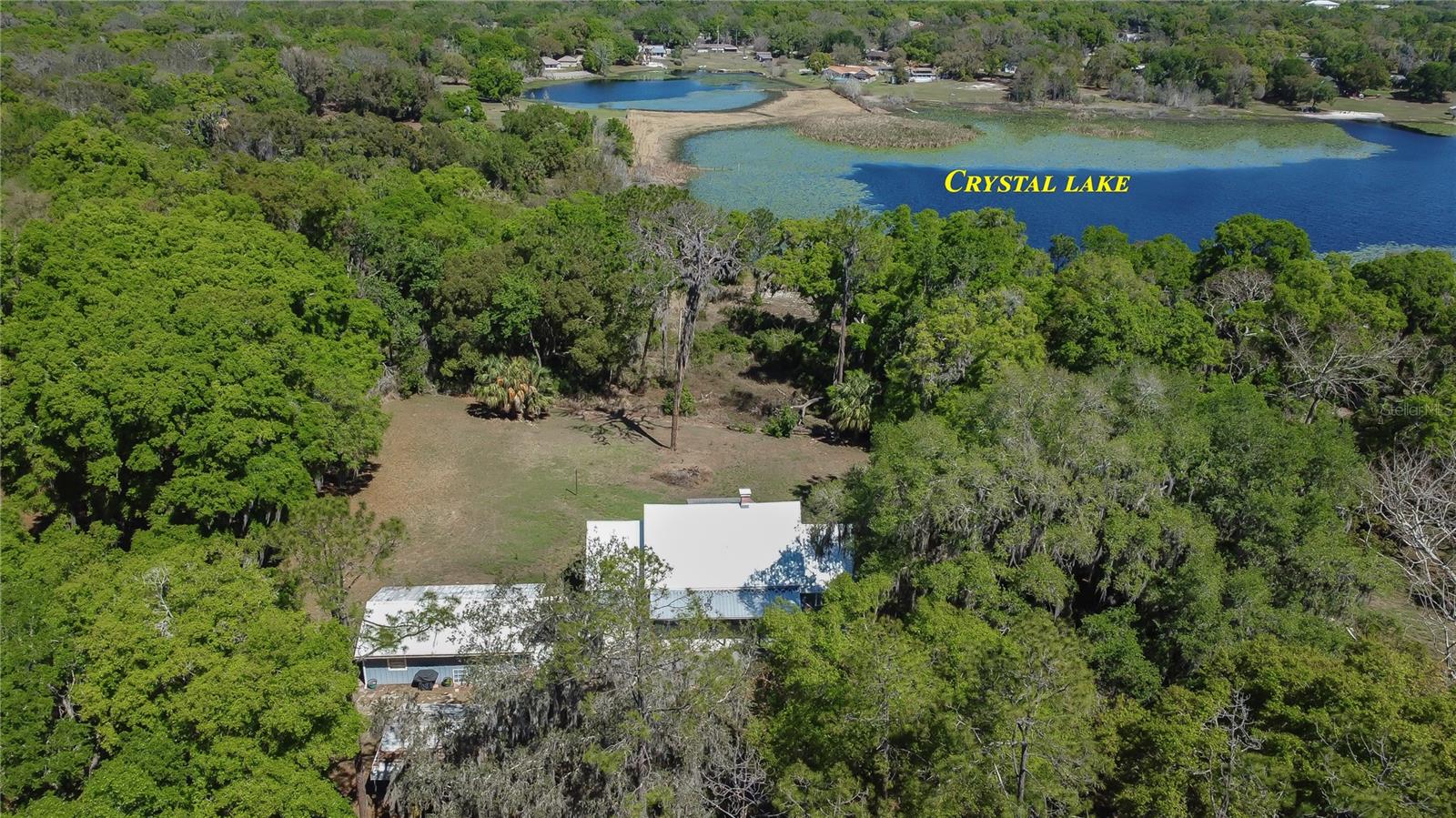 NEARLY 8 ACRES OF WATERFRONT PROPERTY AND FARMHOUSE JUST MINUTES FROM THE VILLAGES, FL ! Imagine waking up each morning to peaceful water views, enjoying coffee on the porch as the sun rises over the lake, and ending your day surrounded by the tranquility that only acreage living can provide. Whether you're dreaming of a private retreat, hobby farm, family compound, or simply more room to live and play, this property offers the flexibility to make that vision a reality. Store your boat and RV, plenty of room to add a pool.  Nestled on 7.74 acres with a beautiful view of Crystal Lake, this unique property offers privacy and character in the heart of Fruitland Park. The historic main home, originally built in 1925, blends timeless charm with thoughtful updates with plenty of functional space. (1 acre of the 7.74 acres is a separate lot). The main residence features 3 bedrooms and 3 bathrooms.  There are two bedrooms downstairs with walk-in closets, shower tub combination and standalone shower. Inside you will find a spacious family room with a cozy wood-burning fireplace, multiple flooring types including wood, tile, vinyl and brick. Charming barn doors add rustic character throughout the home. This property offers abundant storage space, making it both practical and comfortable for everyday living. Recent updates include HVAC replacement in 2020, Tin roof in 2025, underground utilities, new plumbing pipes, providing peace of mind for future owners.  Enjoy the outdoors from the front porch or back porch overlooking the expansive acreage and water view, which could be cleared to reach the water. Additional improvements include a detached garage with a washer and dryer, a bathroom, and a guest room, workspace or storage, along with a separate shed. Most of the property is fenced, providing flexibility for your pets, gardening or recreation. Enjoy the freedom of country living without sacrificing convenience. Located near The Villages and major thoroughfares, you'll have easy access to golf, dining, entertainment, medical facilities, and shopping while returning home to your own private lakefront sanctuary. If you've been searching for acreage, waterfront views, historic character, and unlimited potential, 1905 Myrtle Lake Avenue deserves a place at the top of your list.