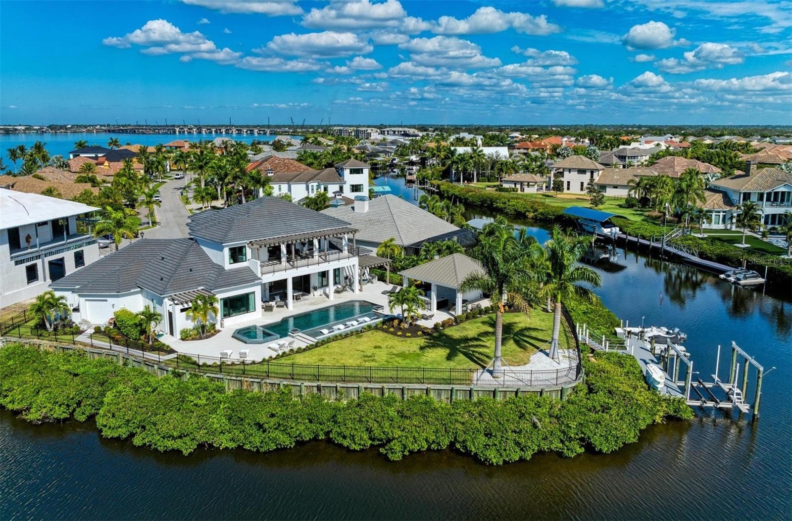 Experience the epitome of modern luxury living at the Reserve at Harbour Walk in a fully furnished distinctive residence featuring 4 bedrooms and 6 bathrooms across two captivating stories. Situated on an idyllic cul-de-sac waterfront lot, where four canals converge and open into the Manatee River, this home offers unparalleled lifestyle benefits. As you step through the grand two-story foyer, revel in the seamless flow of living spaces that connect the main living area, a spacious kitchen, and an inviting dining area. Indulge your culinary desires in the gourmet kitchen, equipped with top-tier Dacor appliances, a 6-burner gas cooktop with a dual oven range, and an expansive island featuring Cambria quartz countertops. The "disappearing corner" sliders extend the first floor to your private waterfront retreat-a 43' saltwater pool with an oversized sun shelf, cascading waterfall, and an 8-person spa. Complementing the pool is a complete outdoor kitchen under a 26x24 cabana, with a natural gas grill, two refrigerators, bar seating, and a separate dining table, accompanied by a tastefully designed pool bath and outdoor shower. An installed Mosquito Joe pest system enhances your outdoor living and dining. The property extends further to a private Trexx dock with a canopy covered 24,000 lb. boat lift, and dual jet ski floating platforms.
Inside, meticulous details abound, from custom-designed ceilings to a great room featuring a fireplace on the feature wall, seamlessly connecting to the gourmet kitchen and dining area-all with breathtaking views of the backyard resort. Wake up to awe-inspiring views in the first-floor owner's suite, designed for ultimate comfort and relaxation. This personal retreat includes custom his and hers walk-in closets and a spa-like bathroom with a separate soaking tub, an oversized dual-entry shower, and sliding glass doors leading to a luxurious private outdoor shower under a trellis. For added privacy, two secondary ensuite bedrooms on the first floor cater to guests or serve as an in-law suite. An elevator adjacent to the great room adds accessibility to the upper living area, and the first-floor powder room is accessible from both inside and out. Ascend to the second floor, where a bonus room with a wet bar awaits, complete with a microwave, wine cooler, ice maker, and dishwasher. Twelve-foot sliders in the bonus room open to a 15x40 balcony, offering unrivaled views of the surrounding canals and the backyard oasis. The second floor also boasts a fourth ensuite bedroom with sliders opening to the balcony. Additional features include a 4-car tandem garage with ample space for a golf cart or workshop. Whether you seek relaxation by the pool or aspire to entertain guests in style, this residence presents itself as a personal oasis for enjoying life's moments-from sunrise to sunset and beyond. Located in The Inlets, the Gulf Coast's premier gated waterfront community with deep water dockage, this home offers easy access to the historical districts of Bradenton, the cultural charm of Sarasota, and the excitement of Tampa and St. Pete. Live the dream in this exceptional residence that seamlessly blends sophistication with the joy of waterfront living.