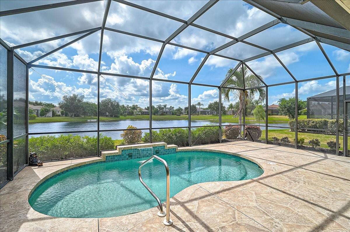 Perfectly positioned to capture breathtaking long lake views, this beautiful residence offers the ideal blend of comfort, functionality, and Florida living.

Featuring 2 bedrooms, 2 bathrooms, a dedicated office/den, and a spacious 2-car garage, this home is designed for both everyday enjoyment and effortless entertaining. From the moment you enter, your eyes are drawn through the open-concept living space to the sparkling heated pool and expansive water views beyond. The seamless flow between the kitchen, dining area, and living room creates a bright and welcoming atmosphere, making it easy to stay connected with family and guests while enjoying the tranquil lakefront setting.

The kitchen offers abundant cabinetry, generous counter space, and a large pantry that provides exceptional storage. Whether preparing a casual breakfast or hosting holiday gatherings, you'll appreciate the thoughtful layout and convenient access to the main living areas.

Architectural details add character throughout the home, including elegant coffered ceilings in both the living room and the spacious primary suite. The owner's retreat is a peaceful sanctuary overlooking the water and features engineered hardwood flooring, large walk-in closets outfitted with custom built-in shelving and drawers, and a well-appointed ensuite bathroom with dual sinks, ample vanity space, and a walk-in shower.

Storage has been carefully considered throughout the home, with professionally designed closet systems maximizing every inch of available space. The office/den, also finished with engineered hardwood flooring, offers flexibility as a home office, hobby room, library, or guest space.

The home features solid surface flooring throughout, with ceramic tile in the main living areas and engineered hardwood in the primary bedroom and office, providing both beauty and ease of maintenance.

Step outside and discover one of the property's most impressive features. The heated pool overlooks a picturesque lake, creating the perfect setting to relax with a morning cup of coffee, entertain friends, or unwind while enjoying spectacular sunsets reflected across the water. The aluminum pool cage has been reinforced and updated to provide added confidence during Florida's storm season while preserving unobstructed views of the surrounding landscape.

Significant improvements have already been completed, allowing the next owner to move in with confidence. Impact-rated windows were installed in 2022, providing enhanced storm protection, energy efficiency, and peace of mind. A tankless water heater was installed in 2019, offering endless hot water and improved efficiency. Most recently, the air conditioning system was replaced in June 2026, ensuring years of dependable comfort.

The oversized 2-car garage is equally impressive, featuring a durable epoxy-coated floor and sturdy built-in hanging storage shelves that help keep tools, seasonal items, and household belongings neatly organized.

Opportunities like this are increasingly difficult to find—a home that has never before been offered for sale, thoughtfully updated, meticulously maintained, and positioned on a beautiful waterfront homesite. Whether you are seeking a full-time Florida residence a storm retreat from an island home or a seasonal retreat, this exceptional property offers the perfect combination of comfort, quality, and scenic beauty.