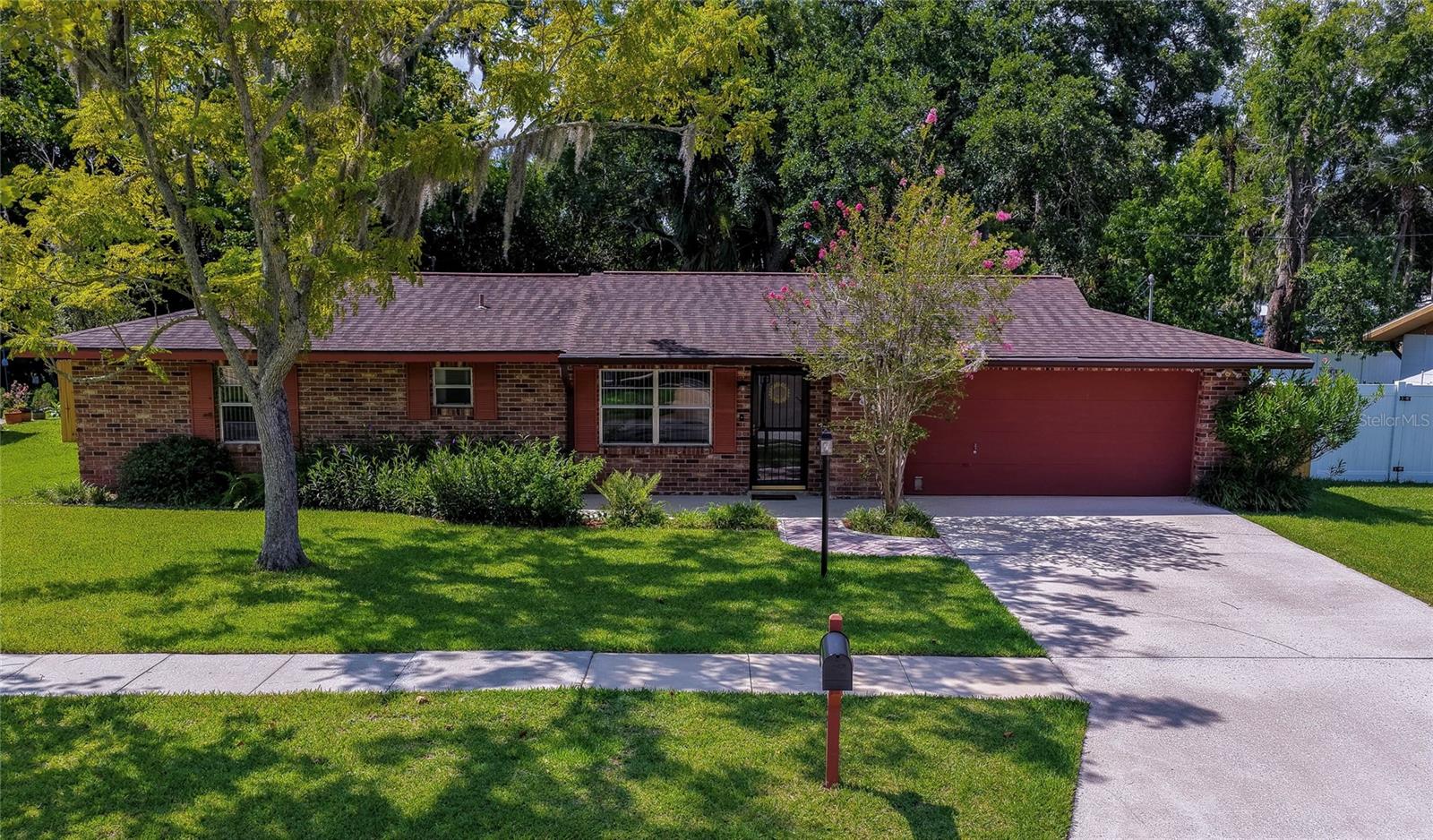 Virtually Staged. This meticulous 2-bedroom, 2-bathroom home in Big Tree Village featuring an abundance of updates, offers a combination of modern comfort and exceptional outdoor enjoyment. Freshly painted interior and exterior. The attractive brick exterior, mature lush landscaping, and attached two-car garage create inviting curb appeal, while the expansive fenced backyard provides a private setting surrounded by beautiful shade trees. The bright and inviting interior features luxury vinyl flooring with additional underlayment throughout, abundant natural light, and seamless access to the screened lanai. The kitchen is designed for everyday functionality with newer stainless steel appliances, quartz countertops, ample cabinetry, and convenient access to both the dining area and lanai. The spacious primary suite offers a walk-in closet with extensive storage and an updated ensuite bathroom featuring a beautifully tiled walk-in shower and stylish vanity with a granite countertop. A comfortable secondary bedroom and updated guest bathroom provide flexibility for family, guests, or a home office. Step outside to the screened lanai overlooking a private fenced backyard with lush lawn space, mature landscaping, and a detached storage shed with ramp access. The expansive lot provides plenty of room for outdoor activities, gardening, or simply enjoying the peaceful surroundings beneath the canopy of established shade trees. The huge steel framed shed is perfect for a workshop. The lush lawn and surrounding landscaping are kept vibrant year-round by a 4-zone sprinkler and misting system. With no HOA, homeowners enjoy added flexibility and fewer restrictions. Great location just minutes from the Intracoastal, the World's Most Famous beach, dining, shopping and entertainment. All information recorded in the MLS is intended to be accurate but cannot be guaranteed.