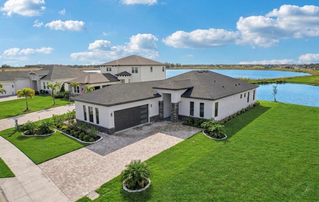 One or more photo(s) has been virtually staged. Experience modern waterfront living in this newly built (2024), never-lived-in 4-bedroom, 3-bath, 2,533 SF single-family home designed for comfort, efficiency, and effortless everyday living. A standout feature is the thoughtfully designed multi-generational suite, complete with its own private entrance and full bathroom—an ideal space for in-laws, guests, long-term visitors, or a dedicated work-from-home retreat. Additionally, every bathroom is equipped with a bidet!
The open floor plan centers around a beautifully appointed gourmet kitchen featuring GE Profile stainless steel appliances, an oversized island with additional storage, and elegant custom cabinetry. Porcelain tile flooring flows throughout, enhancing the home’s clean, contemporary aesthetic. Large windows and a three-panel sliding glass door frame peaceful views of Lake Medora, creating a seamless connection between indoor and outdoor living. The screened lanai includes an outdoor-kitchen-ready outlet, perfect for lakeside dining and gatherings.
The owner’s suite offers a serene escape with tranquil lake views, a custom walk-in closet, and a spa-inspired bathroom. Additional upgrades include insulated windows, an insulated garage door, finished garage walls, and an AO Smith hybrid water heater.
Residents enjoy resort-style amenities including gated entry, multiple lake access points, fishing piers, boat ramps, a clubhouse with full kitchen, three pools (one heated), tennis, basketball, and pickleball courts, plus a state-of-the-art fitness center with saunas. Enjoy golf-cart or walking access to the Water Ridge clubhouse and its regularly hosted community activities.
Call this home today—you’ll be glad you did.