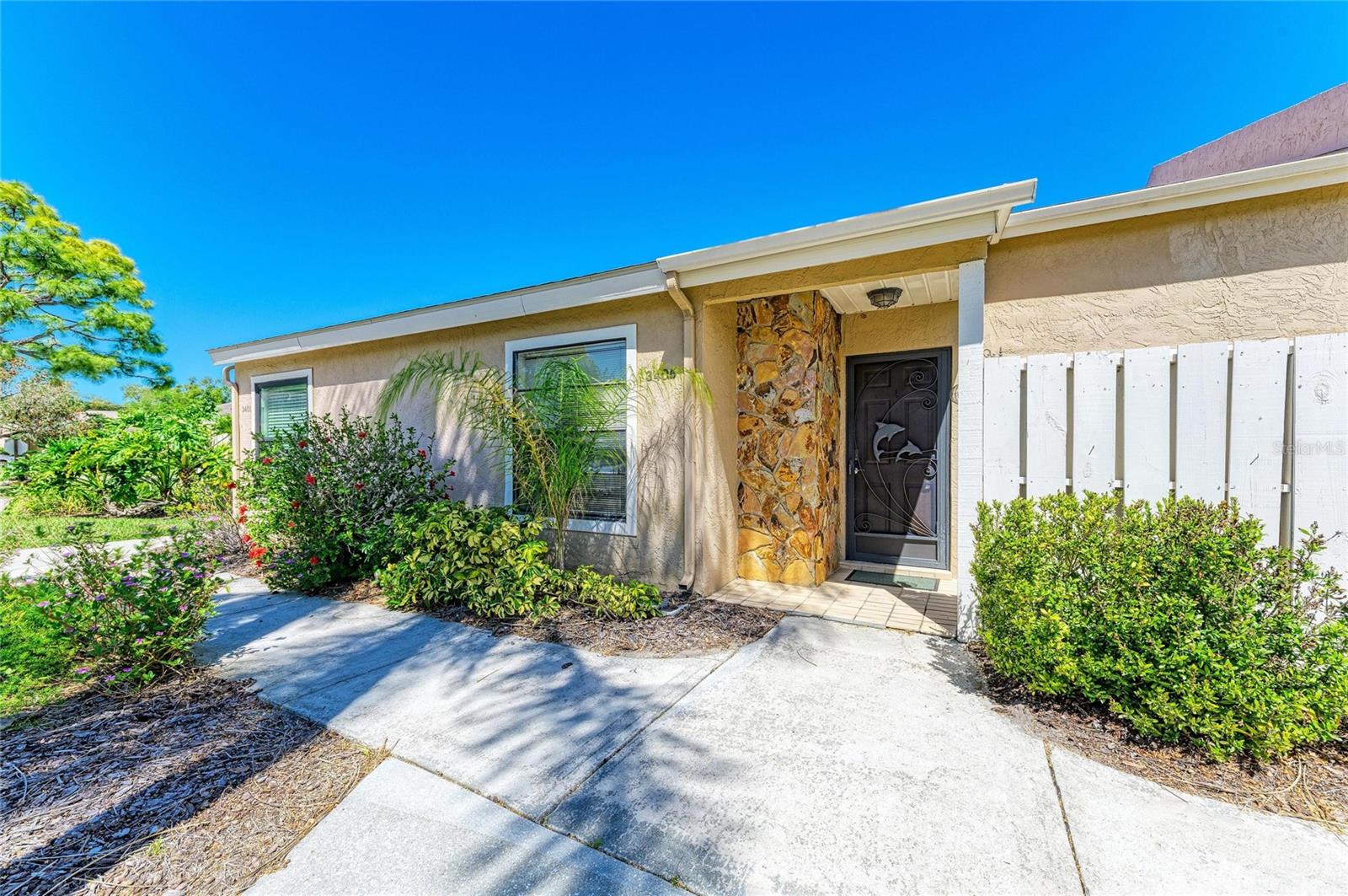 Experience the ultimate blend of comfort and tranquility in Tallywood, a beautifully maintained 55+ villa community nestled in a prime Sarasota location. This inviting residence features a private, screened front door with a courtyard perfect for grilling or soaking up the Florida sunshine. Inside, the open floor plan seamlessly connects the kitchen to both living areas, creating an ideal layout for entertaining guests. The rear great room has been thoughtfully enlarged to incorporate the original lanai, offering additional square footage and serene views of the lush, park-like landscaping. A spacious primary suite serves as a true retreat with an expansive walk-in closet, while the unit includes a covered one-car carport with a dedicated storage cabinet. Residents enjoy resort-style amenities including a clubhouse, screened pool, shuffleboard, and fitness center, all situated just minutes from downtown Sarasota, world-class Gulf beaches, UTC Mall, and I-75. Discover the maintenance-free lifestyle you deserve and schedule your private tour of this Tallywood gem today