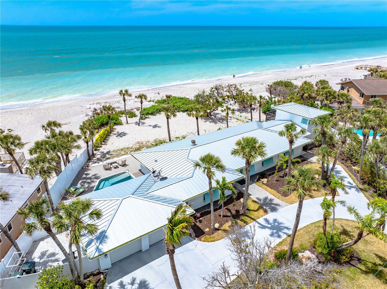 One or more photo(s) has been virtually staged. Timeless Gulf-Front Dream Home with Guest House. Experience coastal elegance in this extraordinary 4-bedroom beachside estate, perched high on nearly an acre with 150 feet of pristine private beachfront. Designed with light, space, and craftsmanship in mind, this home offers sweeping Gulf views and effortless indoor-outdoor living.
The gourmet kitchen is a chef’s delight, featuring quartz countertops, a large island, built-in desk, and professional-grade appliances. Entertain with ease in the spacious dining room and open-concept great room with a cozy fireplace and multiple seating areas for both comfort and sophistication. Bathrooms are adorned with beautiful Carrera marble, while the full-size laundry room offers abundant cabinetry and a utility sink. Natural hues and light-filled interiors provide a serene backdrop for everyday living.
Connected by a breezeway, the two-story guest house offers the same charm and quality as the main residence—perfect for guests or extended family.
Outside, enjoy a walk-in pool, swaying palms, and manicured tropical landscaping—all just steps from your secluded beach. Partially fenced for privacy, this is truly a rare and refined coastal retreat.