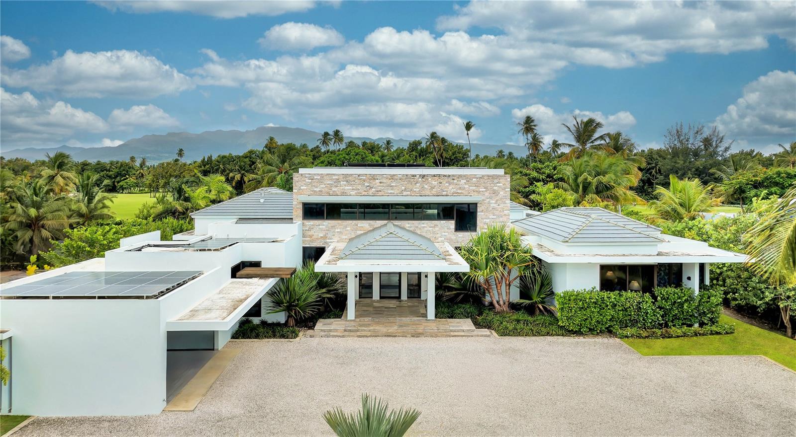 ***SOLD*** No expense spared on this true to form Caribbean contemporary new construction, sitting blissfully at the eastern entrance to the rainforest and within the gates of Bahia Beach Resort. Completed in 2024, 23 Las Estancias stands a testament in true adoration to architectural intention and sophisticated purposeful interior design. Sitting on just over 1/2 acre, each curated detail resonates throughout this 3 bedroom, 3 full bath and 2 partial bathroom single level estate. 20+ Ft entry ceilings pull all of the natural light from the floor to ceiling glass doors, with  broad facing western exposure to the lake, mountains and lush tropical backdrop that only the El Yunque rainforest can afford. Brushed blond wood palettes delicately accent the pinnacle of each room's ceilings, pulling in natural textures to the all concrete structure. Limestone floors add a cool tonality to the juxtaposition of ultra green foliage enveloping the home's elevated exterior facade landscaping. Cascading honed marble countertops highlight this double sized gourmet kitchen, featuring a gratuitous 19x19 footprint, and cornered by 10+ ft glass doors that open fully to the property’s magical oasis. Privacy and purpose reign here, where your outdoor summer kitchen equipped with full gas range, sink and bar moves fluidity towards your zero edge swimming pool, which is adjacent to your outdoor shower and bath, dining, sunning areas and hidden entertaining spaces. Guest suites, each highlighting the exotic nature of living within the resort, feature walk-in closets, ensuite baths and full length picture windows encasing the spaces with fresh sunkissed natural light. The primary wing serves as an homage to refined peace. Double entry doors swing inwards towards the 4 post california king bed, masterfully angled towards the estate’s western outdoor living, where hints of running water from the lake abutting the property’s line, and coconut bearing palms sway off in the distance, to this coast's constant melodic breezes. A basin tub swathed in the greenery exposed by the large bay windows, and indoor/outdoor shower textured in raw stone elements, and an 11' 11” X 13' 11” temperature controlled boudoir and closet round out the home's impeccable design. Warm neutrals kiss every element of design here, where Lutron lighting and shades throughout, a fully off grid solar installation on roof and numerous other refined details, allow the owner the ease of purposeful living. 23 Las Estancias serves as a culmination of vision and passion elegantly aligned in both presence and form. The only of its kind, a true 1 of 1.