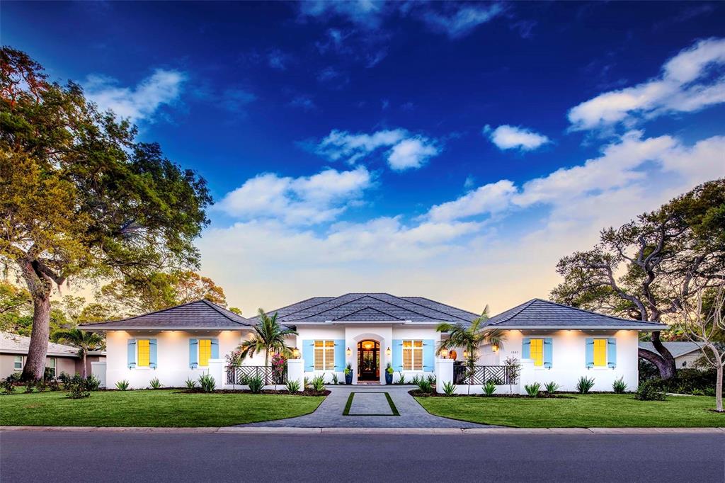 Live a life of elegance as you relish seamless indoor-outdoor living in this stunning 2016 four-bedroom, four-and-a-half-bathroom custom-built home with a tropical feel that will satisfy your vacation cravings year-round. Appointed with gorgeous designer fire bowl water fall features, fire pit, chlorine-free pool and spa overlooking the tranquil lake while views from the covered patio allow you to soak in the complete natural experience. The home’s lush landscaping extends to the front of the home where the driveway leads your eyes to the stylish split design. As you enter through the custom front door and screen adorned with an extensive wood ceiling feature, the foyer opens to vaulted ceilings giving an airiness to the open-concept design. Dual offices/den offer flexible workspaces. The master bedroom offers a generous sitting area and views and access to the pool and covered porches as well as an elaborate bath with a spacious private outdoor shower.  Decorative lighting fixtures act as landing points throughout the space, with a central chandelier in the living room and the eat-in kitchen area, as well as a trio of pendants above the large kitchen island and breakfast bar. Plenty of natural light floods the living areas with full walls of sliding pocket doors on the back of the home. The ease of transitioning to the outdoor areas allows you to extend the use of endless space for any occasion.
