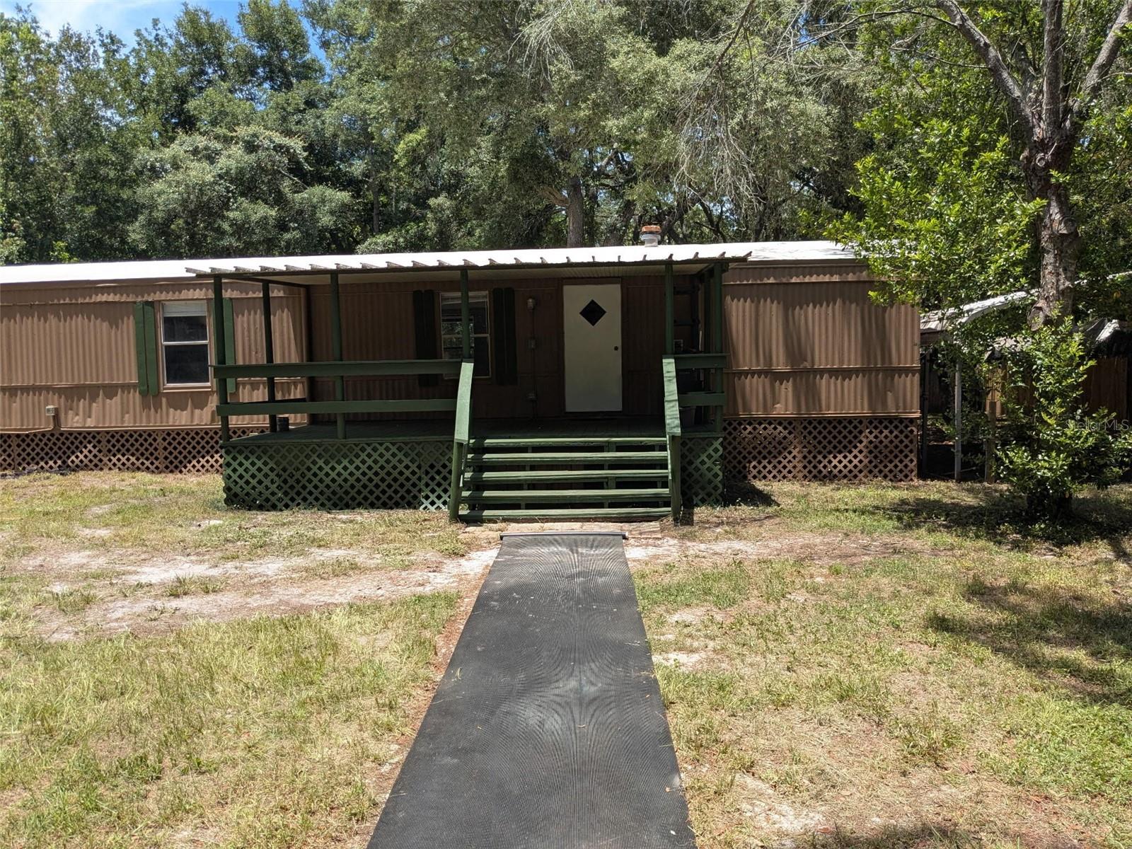 You will not find another property in Pasco County with this amount of infrastructure and value add at THIS PRICE POINT!

Set back behind a long private driveway on a fully fenced one-acre lot, this 2-bedroom, 2-bath home is peaceful.  The land is one of the best parts of the property, with mature trees, natural garden areas, vines, open usable space, and trails that make the yard feel almost like your own private park.  

There are places to wander, places to sit, places to garden, and places that already feel naturally sheltered. A tree-lined path runs through the property, with smaller pockets of privacy throughout the yard that could easily become a reading spot, bench area, fire pit, or a courtyard. It is peaceful, usable, and full of character without feeling overdone.

The property includes outdoor electrical outlets by house and outbuildings, an elephant ear garden, native mullein, loquat trees, blackberry bushes, strawberries, tomatoes, citrus, cherry, lime, and orange trees, creating a landscape that feels established, lush, and alive. It is the kind of yard that gives you something to notice every time.

The 1986 mobile home has a thoughtful split-bedroom layout, with the primary bedroom and private bath on one end and the second bedroom and bath on the other, giving the home a comfortable sense of separation. Recent improvements include updated flooring, interior paint, drywall work, newer toilets, a newer electric range, washer and dryer, and a new water heater installed in 2025.

Major systems have also been addressed, including a new drain field, newer well pump and bladder, and significant electrical upgrades since 2022. The property also includes both 30-amp and 50-amp RV hookups, making it well suited for RV parking, guests, projects, or flexible outdoor use.

Outside is a small detached tiny-home-style structure with its own covered front porch, an additional outbuilding with washer/dryer hookups, two pole barns, a covered front porch, a back deck, an outdoor shower, and multiple usable outdoor areas all with electricity and water access. Whether you want storage, workspace, garden space, guest space, or simply room to spread out, this property gives you options.

Even with all that privacy, the location remains convenient to everyday essentials like Publix, banking, gas, shopping, and other nearby services. It gives you the feeling of being tucked away without feeling cut off.

This is not a cookie-cutter property. It is private, green, practical, and full of quiet possibility — a place where the land itself feels like part of the home.

1986 mobile home
2 bed/2 bath
AR Zoning, You own the land
Split-bedroom layout
Primary bedroom with private bathroom
TPO Membrane Roof replaced in 2020
Fully fenced 1-acre lot
Mostly newer fencing
Long private driveway
Covered front porch
Back deck
Two pole barns
Detached tiny-home-style structure with covered porch
Additional outbuilding with washer/dryer hookup potential
30-amp RV hookup
50-amp RV hookup
New drain field since 2022
Newer well pump and bladder since 2022
Significant electrical upgrades since 2022
New water heater in 2025
Updated flooring
Newer toilets
Newer electric range/oven
Newer washer and dryer
Fresh interior paint/drywall updates
Elephant ear garden
Native mullein
Loquat trees
Blackberry bushes
Strawberries
Tomatoes
Citrus trees
Tree-lined paths
Private yard areas / natural sitting spots
Close to Publix,