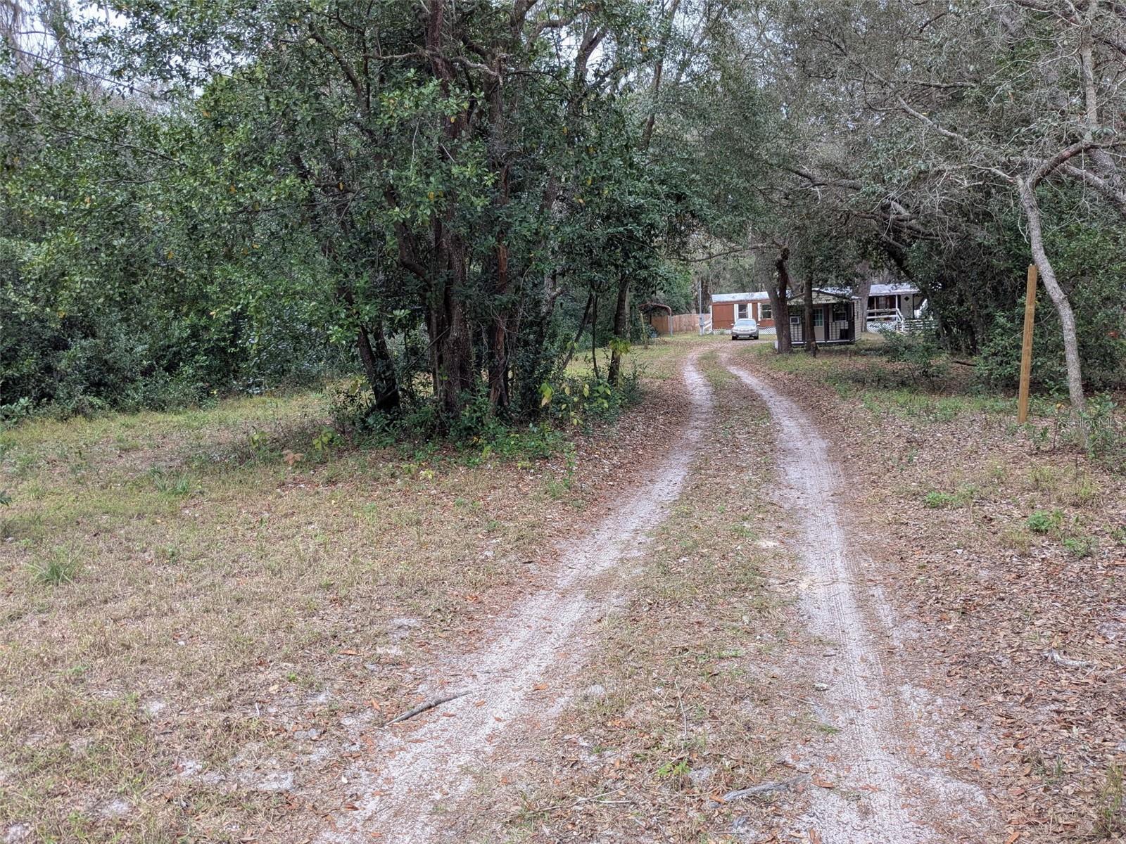 You will not find another property in Pasco County with this amount of infrastructure and value add at THIS PRICE POINT!

Set back behind a long private driveway on a fully fenced one-acre lot, this 2-bedroom, 2-bath home is peaceful.  The land is one of the best parts of the property, with mature trees, natural garden areas, vines, open usable space, and trails that make the yard feel almost like your own private park.  

There are places to wander, places to sit, places to garden, and places that already feel naturally sheltered. A tree-lined path runs through the property, with smaller pockets of privacy throughout the yard that could easily become a reading spot, bench area, fire pit, or a courtyard. It is peaceful, usable, and full of character without feeling overdone.

The property includes outdoor electrical outlets by house and outbuildings, an elephant ear garden, native mullein, loquat trees, blackberry bushes, strawberries, tomatoes, citrus, cherry, lime, and orange trees, creating a landscape that feels established, lush, and alive. It is the kind of yard that gives you something to notice every time.

The 1986 mobile home has a thoughtful split-bedroom layout, with the primary bedroom and private bath on one end and the second bedroom and bath on the other, giving the home a comfortable sense of separation. Recent improvements include updated flooring, interior paint, drywall work, newer toilets, a newer electric range, washer and dryer, and a new water heater installed in 2025.

Major systems have also been addressed, including a new drain field, newer well pump and bladder, and significant electrical upgrades since 2022. The property also includes both 30-amp and 50-amp RV hookups, making it well suited for RV parking, guests, projects, or flexible outdoor use.

Outside is a small detached tiny-home-style structure with its own covered front porch, an additional outbuilding with washer/dryer hookups, two pole barns, a covered front porch, a back deck, an outdoor shower, and multiple usable outdoor areas all with electricity and water access. Whether you want storage, workspace, garden space, guest space, or simply room to spread out, this property gives you options.

Even with all that privacy, the location remains convenient to everyday essentials like Publix, banking, gas, shopping, and other nearby services. It gives you the feeling of being tucked away without feeling cut off.

This is not a cookie-cutter property. It is private, green, practical, and full of quiet possibility — a place where the land itself feels like part of the home.

1986 mobile home
2 bed/2 bath
AR Zoning, You own the land
Split-bedroom layout
Primary bedroom with private bathroom
TPO Membrane Roof replaced in 2020
Fully fenced 1-acre lot
Mostly newer fencing
Long private driveway
Covered front porch
Back deck
Two pole barns
Detached tiny-home-style structure with covered porch
Additional outbuilding with washer/dryer hookup potential
30-amp RV hookup
50-amp RV hookup
New drain field since 2022
Newer well pump and bladder since 2022
Significant electrical upgrades since 2022
New water heater in 2025
Updated flooring
Newer toilets
Newer electric range/oven
Newer washer and dryer
Fresh interior paint/drywall updates
Elephant ear garden
Native mullein
Loquat trees
Blackberry bushes
Strawberries
Tomatoes
Citrus trees
Tree-lined paths
Private yard areas / natural sitting spots
Close to Publix,