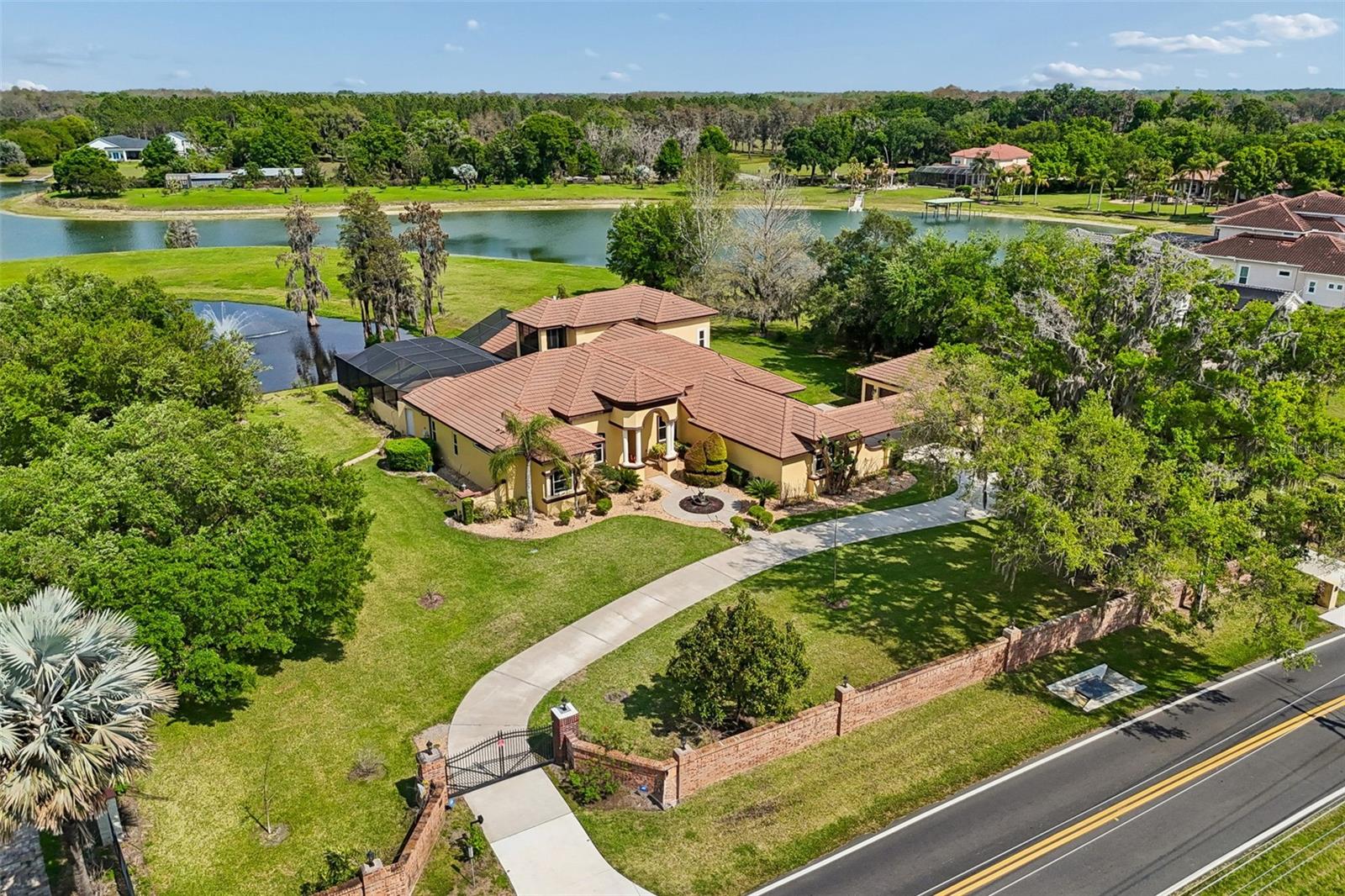 This exquisite lakefront estate masterfully blends elegant living with the tranquility of nature. Spanning almost three acres, with over 200 feet of pristine Lake Breckenridge frontage, the property offers kayaking, jet skiing and boating. The electronically gated entrance introduces a meticulously landscaped realm, featuring a serene pond with a captivating, lighted fountain and abundant space for bespoke additions like a private dock or fun sport courts. Within, discover a residence of refined living that exemplifies the current design preference for modern Tuscan architecture, a style that balances the warm finishes of rustic charm with contemporary sophistication. Interior finishes include crown molding, attractive wood flooring, and large-format tile. The gourmet kitchen, a culinary enthusiast's delight, is appointed with lustrous quartz countertops and backsplash, custom rich wood cabinetry with integrated pullouts, an expansive center island, a dedicated wine bar, high-end appliances, and a gas cooktop. All four generously proportioned bedrooms are thoughtfully on the main level. Secondary bedrooms offer charming window seats, while a dedicated children’s lounge provides integrated homework centers. A versatile first-floor bonus room, commanding breathtaking lake views, presents the opportunity for a fifth bedroom or an independent in-law suite complete with a private entry, sitting room and en-suite bath. The lavish main primary suite features a private sitting room with panoramic views of the pond and lake, alongside a spa-inspired bath boasting a sumptuous soaking tub, dual vanities, and an expansive walk-in closet with custom built-ins and a central island dresser. A distinguished home office or library offers bespoke wood built-ins and rich wood flooring. Ascend to the upper level to an entertainer's dream, featuring a billiards room with a wet bar, refrigerator and microwave. Adjacent, a state-of-the-art media/theater room offers an immersive experience with a large screen, premium media equipment and stadium seating. A screened upstairs balcony provides an idyllic setting for stargazing or serene contemplation of the picturesque pond and lake. The outdoor sanctuary redefines resort-style living with an expansive 3,000-square-foot lanai designed for grand entertaining. It features a summer kitchen with a grill, refrigerator, and outdoor gas fireplace, an 8-foot-deep heated pool with a luxurious Pebble-Tec finish and heated spa. Further enhancing the grounds with full-property sprinkler irrigation and professional landscaping with LED lighting. Automotive enthusiasts will appreciate the six-car garage capacity offering extended-size garage doors and a 50-amp electric vehicle charger. For paramount security and efficiency, the estate is equipped with impact-resistant PGT and Simonton doors and windows, engineered to withstand winds of up to 200 mph. A whole-house 38-kilowatt Generac generator, powered by a 1,000-gallon buried propane tank, ensures uninterrupted comfort. Energy efficiency is further optimized by 80 LG solar panels and LED lighting throughout the interior. Advanced technology and security provisions include a custom 13-camera video surveillance system with mobile access, a comprehensive whole-house sound system, and sophisticated water purification and softening systems. Enjoy low annual HOA fees of just $600 per year, enhancing the lake-front lifestyle. Don’t miss out on this captivating home and property.
