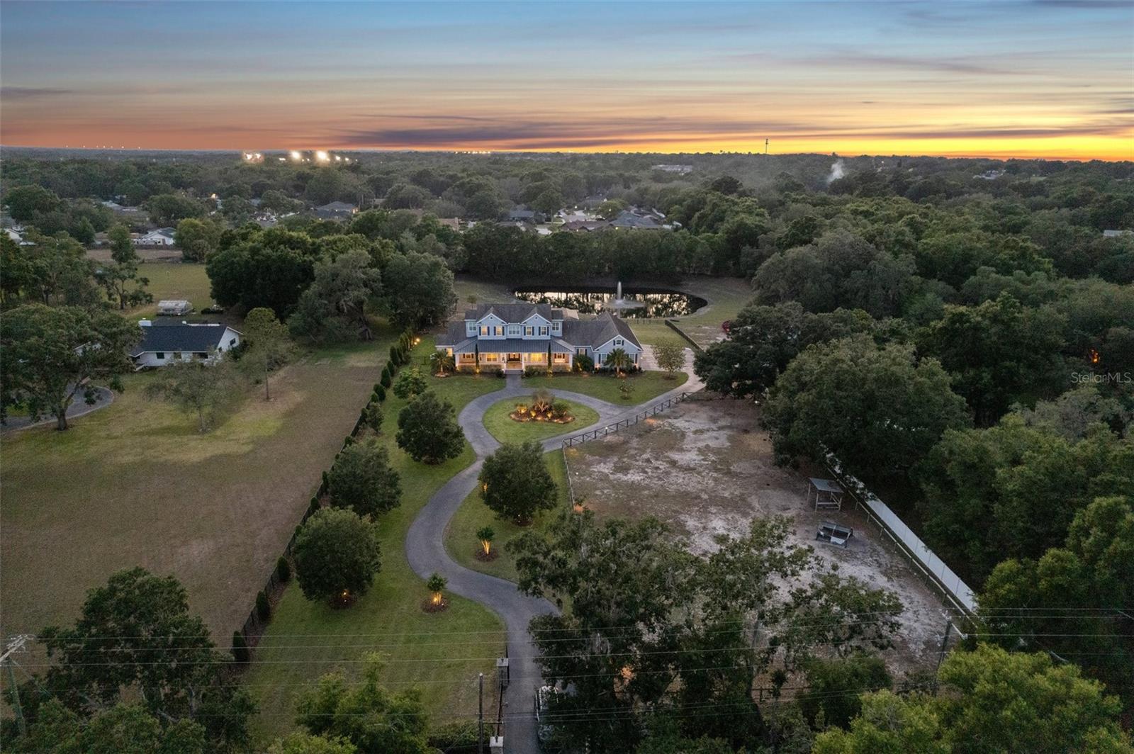 STUNNING LUXURY FARMHOUSE ESTATE feels like it’s straight out of the pages of Southern Living Magazine with its elegant modern design and picturesque surroundings. It is nestled on 4.2 fenced acres overlooking its own private, spring-fed pond and barn, and is conveniently located ONLY 15 miles from Tampa!! Escape to your own majestic peaceful paradise; this one has it all!! it doesn’t get much better than this!! You’ll enter through your private electric gate and drive up the winding driveway to this extraordinary and impressive 6,300 sq ft custom home (9,822 sq ft total) offering 5 bedrooms + 6 full bathrooms + an office/gym + formal sitting room + a theater room and game room with wet bar + an expansive oversized 6-car attached garage + an unrivaled outdoor living space with private resort-style, solar-heated pool with sun-shelf + a large covered impressive outdoor kitchen and lanai PERFECT for entertaining your family & friends! Whole home generator guarantees you are never without power. The charming barn is 1,800 sq ft and offers 6 stalls + a center aisle + feed room + tack room + wash/dressing station + its own half bath + covered front porch! Your new home offers an OPEN FLOOR PLAN with high ceilings making it light, bright and spacious! You have upgrades everywhere including crown molding in every room, plantation shutters, real wood cabinets, quartz and granite countertops throughout the entire home. All the bathrooms have ceramic tiled floors and showers with glass doors. The main living spaces have engineered hardwood floors. The spacious island-style chef’s gourmet kitchen has been recently remodeled and is the heart of this home; it is open to the large great room and dining room all with large glass doors offering views of your inviting pool, pond, and pastures!!  The luxury kitchen is expansive with complementing rooms to include a large walk-in pantry + a large butler’s pantry with an extra refrigerator + a dry bar/coffee bar area + an ENVIOUS laundry room with dual washers and dryers + the home also offers a “Costco Room” to store all the items your family needs!  You have more storage area in this home than you could ever wish for! All of these rooms have recently been remodeled with gorgeous modern Quartz countertops and backsplashes and have real wood cabinets! The kitchen offers all stainless steel luxury appliances to include 2 dishwashers, built-in double ovens, a Wolf gas cooktop, pot-filler, wine fridge, and ice-maker. The kitchen also has a large breakfast bar + additional seating at the island. 4 of the bedrooms have their own ensuite bathroom (what everyone wishes for) + walk-in closet with custom closet organizers!! The master bedroom is downstairs and large enough to boast its own cozy living room with a modern stone fireplace and private door to the outside lanai with outdoor living room! The master ensuite bathroom offers dual vanities/sinks with a large jetted tub, spacious walk-in shower, large walk-in closets, door to dog run! Additional downstairs bedroom with ensuite bathroom can be used as an MIL suite. Have a little fun fishing & canoeing, or walk outside down your paver path with a glass of wine to relax and unwind around your fire-pit overlooking your illuminated fountain! NO HOA! Bring the boat, RV, horses, pets, bring it all! Located close to everything...yet tucked away w/privacy & peacefulness! Call today to schedule your private showing of this unforgettable "straight-out-of-magazine" home!! Room Feature: Linen Closet In Bath (Primary Bathroom).