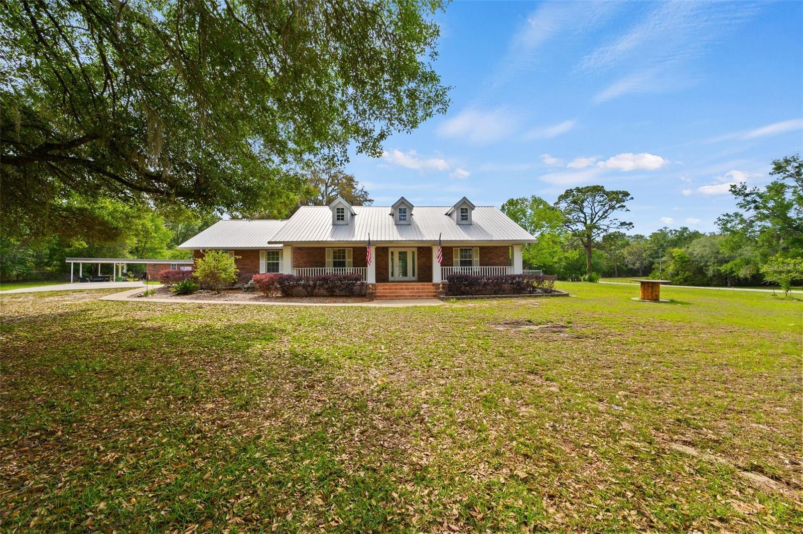 Tucked just over the Gilchrist County line in Newberry, this charming 3-bedroom, 3-bath, brick home sits on 5 beautiful acres, offering the perfect blend of comfort, space, and versatility. Inside, a well-designed layout features formal living and dining rooms, a cozy family room, and a spacious kitchen with additional dining space, separated by a distinctive brick accent wall.
The split floor plan provides privacy for the primary suite, complete with a dedicated office, walk-in closet, and a generously sized bathroom. On the opposite side, two additional bedrooms and baths offer comfortable accommodations for family or guests.
Enjoy Florida living with a screened-in pool, updated pool deck, and convenient pool bath.
The property also offers exceptional storage and workspace, including a massive metal building with height to accommodate RV parking and space to store multiple vehicles a boat etc., plus additional storage buildings and a dog kennel.
A rare combination of acreage, functionality, and location—just minutes from town with the privacy of country living.