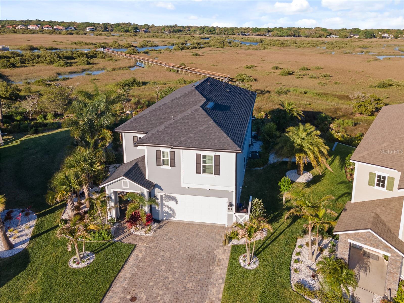 Embrace the boating lifestyle and enjoy premier waterfront living in the highly sought-after community of Antiqua. This gorgeous dock home sits on a large lot with unobstructed views of the St. Augustine Lighthouse, marsh, and a deep-water canal that leads directly to the intracoastal and to the downtown marina in just five minutes by boat. This is the last home on the cul de sac permitted to have a dock, which means there is no dock to the south of you! Enjoy unlimited access to the deepest water in the canal. The private dock is outfitted with underwater lighting, electrical, and water connections—ready for day and night boating adventures. From the moment you arrive, this home impresses with a paver driveway and a welcoming front porch. Inside, the home is thoughtfully designed with rich wood cabinetry, built-ins throughout and stylish updates that make every room feel inviting! The entry foyer sets the tone with elegance, and a practical drop zone is located right off the garage entrance. A guest bedroom and full bathroom downstairs add extra flexibility for hosting. The spacious family room centers around a custom-built entertainment system with an electric fireplace, offering a cozy space to relax and unwind. The kitchen is a showstopper—perfect for the home chef—with a large quartz island, upgraded vent hood, gas cooktop, wall oven, walk-in pantry, and an abundance of cabinetry for storage. There’s even a charming dining area set in front of the bay windows, offering picture-perfect views of the marsh while you dine. Open the triple sliding glass hideaway doors to create a seamless flow to the outdoor living area, where entertaining is effortless. The covered paver patio includes a fully equipped custom outdoor kitchen, a stunning natural stone fireplace, a center island, outdoor ceiling fan, mounted TV, and upgraded surround sound system—everything you need to enjoy the Florida lifestyle year-round. Upstairs, a surprise bonus family area adds another layer of comfort and charm, complete with custom wood beams, built-ins-ideal for entertaining. The primary suite is spacious and serene, offering custom closet organizers, a walk-out balcony with sweeping views of the landscape and a gorgeous ensuite. Start your mornings with a latte on the balcony, catching the sunrise, or unwind at the end of the day with peaceful sunset views. Two additional bedrooms share a large bathroom upstairs, and a spacious utility/laundry room with plenty of folding space adds to the home's functionality. The home is finished with stunning porcelain wood-like tile on level one and luxury vinyl plank flooring on level two, only 1 room has carpeting. Furniture and boat are both negotiable! Antiqua offers residents access to a community pool, clubhouse and kayak launch, and is just minutes from local restaurants, shopping and 1 mile to St. Augustine Beach! Here, you can fish from your dock, spot wildlife in your backyard, listen to concerts from the amphitheater without ever leaving your home, or drive your boat straight to historic downtown St. Augustine. This is waterfront living at its finest—full of nature, activity, and breathtaking views—all from the comfort of your own home. Locals know the Best fishing in all of St. Augustine happens here!