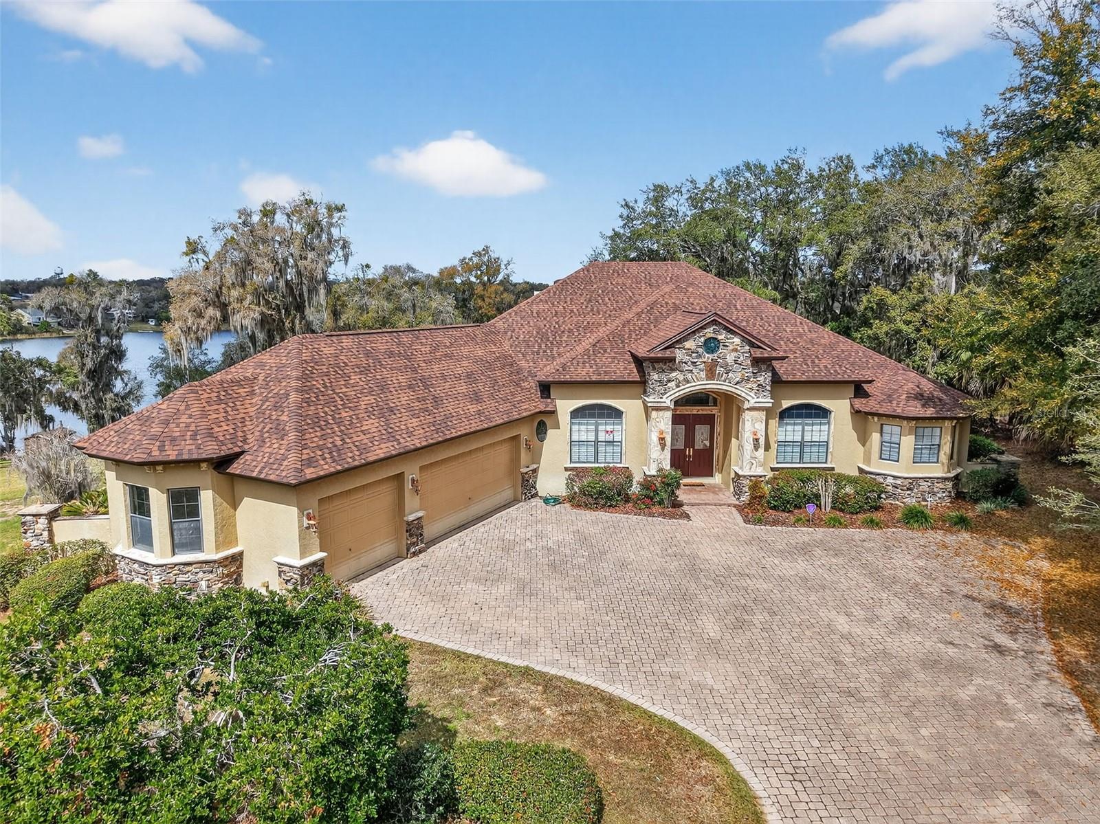 LUXURY ON LAKE NETTIE

PRICE IMPROVEMENT!! Experience the beauty of lake front living on Lake Nettie, ideally situated between charming Mount Dora and Eustis. Privately tucked far from the road, this exceptional residence welcomes you with a long paver driveway, generous parking, and an oversized three-car garage featuring an air-conditioned workshop perfect for hobbies, storage, or projects.
From the moment you enter, the home captures breathtaking views of the water and surrounding landscape. Soaring vaulted ceilings and an open, light-filled floor plan create an elegant, yet comfortable atmosphere designed for both entertaining and everyday living. Multiple gathering spaces including formal living and dining areas, a spacious family room, and a casual dining area adjoining the kitchen offer effortless flow for hosting family and friends.
The primary suite is a serene retreat, showcasing sweeping views of the lake and pool, abundant natural light, and a beautifully appointed bath featuring a walk-in shower and deep soaking tub for ultimate relaxation. A desirable split-bedroom design ensures privacy, with generously sized secondary bedrooms and ample closet space.
Step outside to your own private waterfront oasis. The screened lanai frames a spectacular saltwater pool with cascading waterfall, creating the perfect setting for relaxing afternoons or evening gatherings. Stroll down to the beautiful shoreline to view all the beauty that Florida offers and then gather around the stone fire pit under the stars as the sun sets over the lake.
This remarkable property offers the rare combination of peaceful, resort-style lakefront living with convenient access to shopping, dining, medical care and major roadways, making commuting effortless while preserving the tranquility of your private retreat.