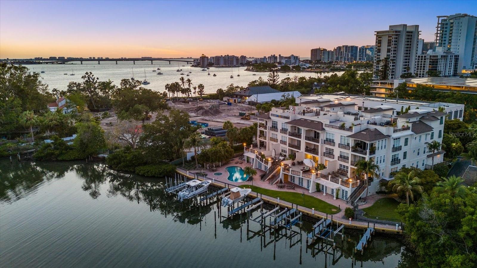 Set within the exclusive 12-residence waterfront enclave of Hudson Crossing, Residence 2C delivers a rare combination of low-density living, private boating access, and refined downtown Sarasota luxury. Included is a boat slip with a 16,000-lb lift, offering effortless days on the water with direct access to Sarasota Bay. Spanning over 2,500 square feet, the residence is highlighted by an exceptional 1,200-square-foot waterfront terrace, among the largest in the community and a true rarity in downtown Sarasota condominium living. Designed for elevated indoor-outdoor entertaining, the terrace features natural gas for grilling, integrated speakers, irrigation, and a private staircase to the pool and docks, creating a seamless connection to the waterfront lifestyle. From the secured garage, a private elevator opens directly into the residence, where expansive living and dining areas feature high ceilings, polished porcelain flooring, and serene water views. The chef’s kitchen is thoughtfully appointed with European cabinetry, a large island, Wolf gas cooktop, Sub-Zero refrigeration, built in oven, microwave and a walk-in pantry. A wet bar and beverage center further enhance the home’s seamless entertaining flow. The fully renovated primary suite offers a tranquil escape with water views, remote-controlled shades, a spa-like bath with dual vanities and walk-in shower, and a custom walk-in closet with center island. Two additional guest suites provide flexibility, including an oversized second bedroom and a third bedroom currently configured as an office with built-ins and a Murphy bed. Additional features include a private two-car garage with EV charger, a ground-level cabana, Lutron lighting, app-controlled HVAC, whole-home water monitoring, remote control shades, central vacuum and a fully integrated Ubiquiti network with hardwired connectivity. Ideally located adjacent to Marie Selby Botanical Gardens, Hudson Crossing offers a boutique waterfront lifestyle just moments from Sarasota’s bayfront, dining, and cultural attractions.