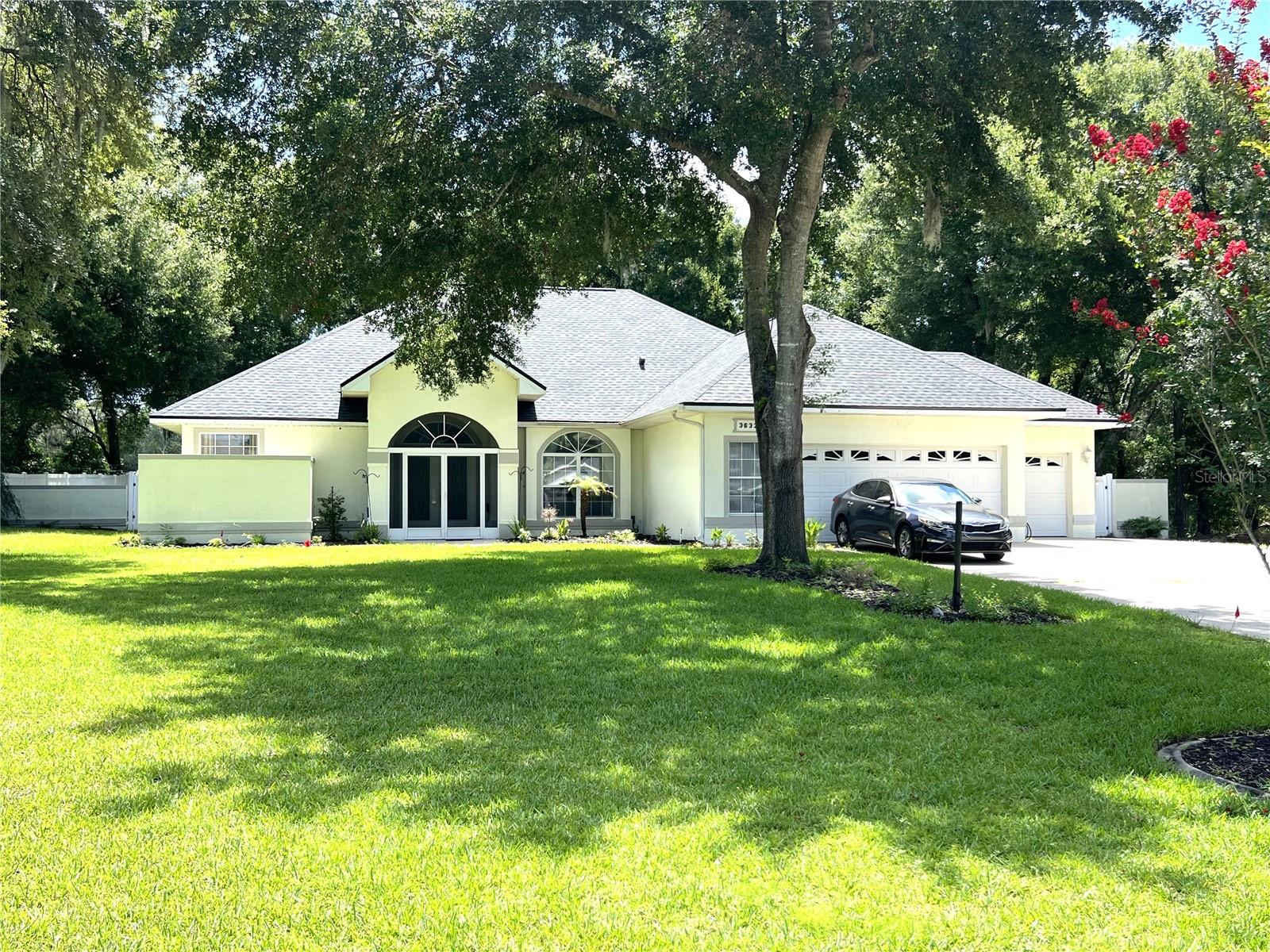 Here are the details of this spacious and stately home in the desirable Spring Lake Pines subdivision. This well-cared-for executive home sits on a 3/4 acre lot and features a three-car garage with an additional parking pad. The interior offers an open floor plan with soaring ceilings, a grand living room, and a formal dining room with beautiful pendant lighting. The kitchen is equipped with ample white cabinetry, a breakfast bar, and included appliances. The primary suite features double walk-in closets and an en suite bath with a jetted garden tub and step-in shower. Two additional bedrooms are located on the opposite side of the home for added privacy. The outdoor space is a private haven, featuring a screened front entrance, a fenced backyard, and a covered lanai. The lanai serves as a perfect gathering space with a half-bath, an outdoor shower, and a hot tub. Key updates include a new roof (2024), a PVCC fence, and an extensive sprinkler system. With low HOA fees, reasonable taxes, and a recently reduced price, this home is ready for its next owner. Schedule a viewing soon!