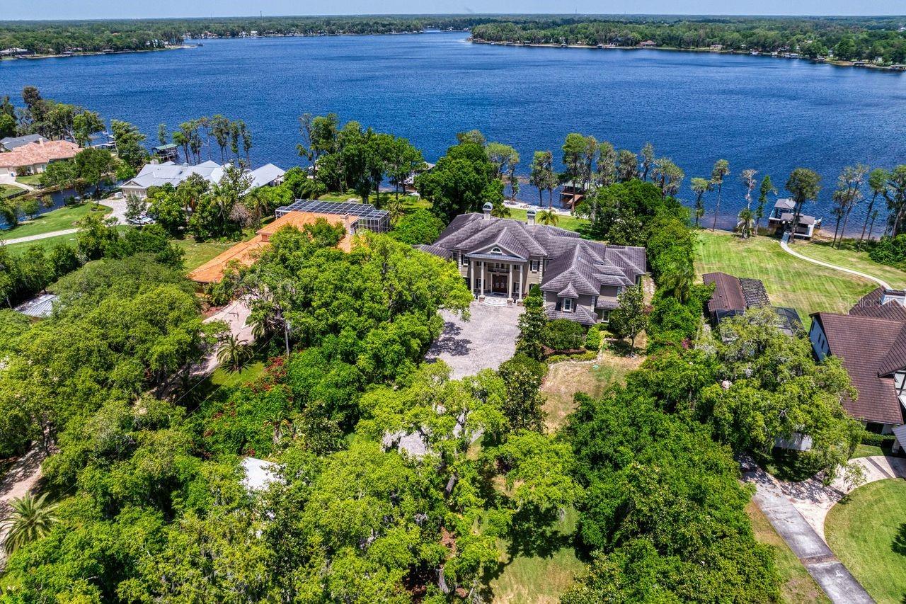 This masterfully crafted eight-bedroom sanctuary represents the absolute embodiment of high-end living within the serene Odessa landscape, presented to the open market for the first time ever. Situated on a sprawling two-acre waterfront estate on the shores of the 434-acre Lake Keystone, the arrival experience is a cinematic journey through double-swing arched wrought iron gates leading to a majestic two-story portico anchored by massive Tuscan columns and a symmetrical facade. Inside, the residence reveals a luminous open floor plan defined by soaring architectural ceilings and polished tan tile flooring. A private elevator provides seamless access to all areas of the 10,357-square-foot compound, ensuring an effortless bridge between the grand social spaces and the upper-level retreats.

The culinary stage is a professional-grade epicenter anchored by a massive granite central island, extensive custom wood cabinetry, and a dedicated wine gallery secured by a grapevine-motif iron gate. For formal occasions, the dining hall is distinguished by a metallic-gold accent wall and an intricate tulip-shaped chandelier.
The interior transitions through a series of specialized wings, including an English-style private office encased in floor-to-ceiling dark wood bookcases, a coffered-ceiling game room with a shuffleboard and custom bar, alongside a tiered cinema equipped with plush leather recliner seating. The upper recreation wing delivers a world-class entertainment experience, while a dedicated fitness center allows for convenient in-home workouts.

The owner’s sanctuary serves as a private wellness retreat, featuring a four-poster canopy bed, an octagonal tray ceiling, and a spa-inspired ensuite with "his and hers" vanities and a deep granite-encased soaking tub. The lifestyle transcends the interior through expansive glass doors that reveal an unparalleled outdoor paradise. A custom-shaped saltwater pool is flanked by raised stone fire pits and an expansive travertine deck. The summer kitchen is equipped with a professional grill and a stone fireplace for evening ambiance. For the modern adventurer, a private boat ramp and a covered boathouse with boat and jet ski lifts provide immediate access to Lake Keystone, while a fully equipped lodge-style guest house ensures absolute autonomy for visitors or extended family.

Engineered for longevity, the 2009 construction has been maintained with meticulous care, featuring exterior masonry paint refreshed within the last four years and major HVAC and water heating systems audited and serviced within the last two weeks. Positioned moments from the storied equestrian trails of Odessa and zoned for the desirable Steinbrenner High School, this high-performance legacy property delivers a distinguished balance of privacy and urban connectivity without concession.