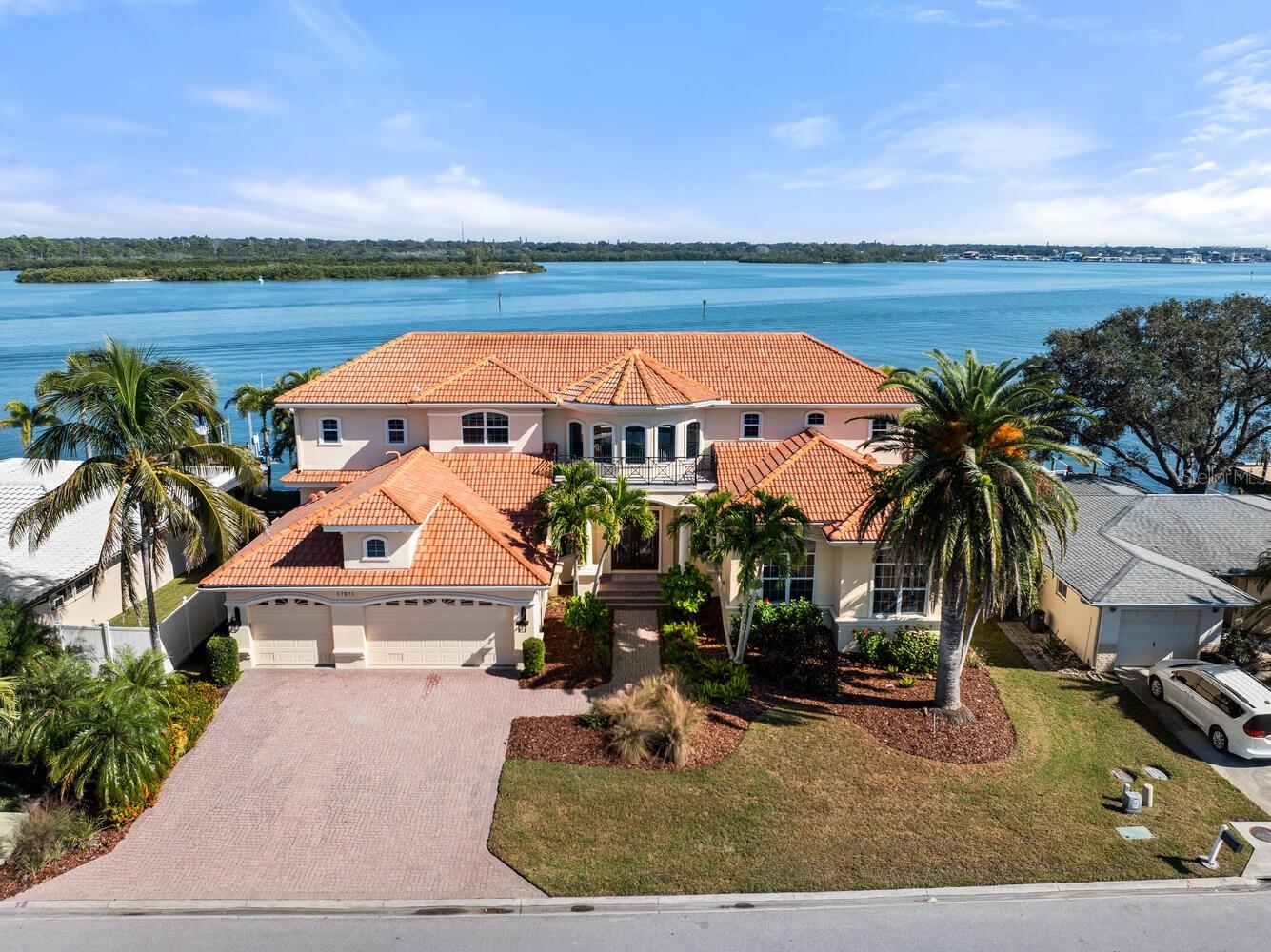 CUSTOM-BUILT WATERFRONT ESTATE ON 100 FEET OF UNOBSTRUCTED WATER VIEWS! This stunning residence offers 4 bedrooms, 3.5 bathrooms, and a private office, blending luxury craftsmanship with panoramic coastal scenery from nearly every room. Nestled in the heart of North Redington Beach along 100 feet of prime waterfront, this luxury custom-built pool home offers the perfect blend of coastal elegance, architectural strength, and resort-style living. Set in a quaint West Coast beach community, the home delivers stunning open-water views from nearly every angle—captured through walls of windows, a sweeping second-floor balcony, multiple covered and open-air patios, and an inviting heated pool and spa.  This 4,142 sq. ft. residence is both sturdy and sophisticated, constructed with a spring tension slab foundation on 70 deep pilings, impact-resistant windows and doors, and thoughtful craftsmanship throughout. Rich interior finishes include custom wood cabinetry, polished granite countertops, detailed tile backsplashes, and dramatic tray and coffered ceilings. Soaring ceilings, stacked windows, and French doors bathe the home in natural light and highlight the breathtaking waterfront backdrop.  The well-manicured front lawn features tropical landscaping framed by mature palms leading you to an impressive two-story foyer. Inside, a curved wooden staircase anchors the grand entrance, complemented by decorative columns, arched windows, tile floors, and a statement metal-and-glass chandelier. The open floor plan flows seamlessly into the dining room, a living room centered around a grand gas fireplace, and a gourmet kitchen equipped with stainless steel appliances, pendant lighting, a 125-bottle wine refrigerator, bar seating, and a charming eat-in breakfast area overlooking the water.  The living room faces the bay directly, offering panoramic water views from every vantage point—perfect for watching dolphins, passing boats, and nightly sunsets. Step outside to an entertainer’s oasis with expansive paver patios, covered lounging space, a sparkling heated pool and spa, and lush landscaping that maximizes privacy while preserving the incredible views.  A massive great room on the first floor provides an additional gathering space ideal for hosting, featuring a full custom wet bar, built-in wood entertainment cabinetry, and ample room for movie nights or sports viewing. The first floor also hosts a spacious half bath for guests, a junior primary suite with an en-suite bathroom, and a well-appointed office/den or bonus room. The custom staircase leads to an airy second-floor atrium filled with natural light and open-water views. Two generous guest bedrooms share a full bathroom, with one bedroom offering direct access to the large waterfront balcony with unobstructed vistas of the Intracoastal Waterway. Double doors welcome you into the luxurious primary suite—a true retreat—featuring its own balcony access, a relaxing sitting area, customized walk-in closets, and an en-suite bathroom with double sinks, a soaking tub, and a walk-in shower.  Parking and storage are abundant with a 773 sq. ft. oversized garage complete with built-in cabinetry, plus a wide paver driveway accommodating multiple vehicles.  For boaters, the property is exceptional: enjoy direct deep-water access, a 25,000-lb boat lift, plus twin jet ski lifts, making it incredibly easy to spend your days cruising the Intracoastal or heading out to the Gulf within minutes.