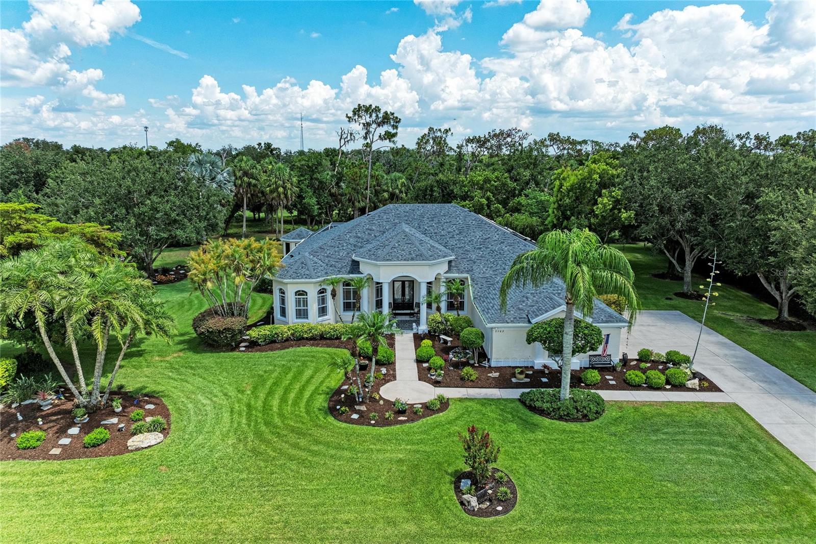 Nestled on a rare, coveted double lot spanning nearly one acre, this exceptional home is located within the prestigious gated community of River Wilderness Golf & Country Club. Beautiful mature landscaping, towering shade trees, and a long driveway create a lasting first impression while providing plenty of parking for family and guests. As you step inside you'll immediately notice the abundance of natural light, high ceilings, and a stunning view of the sparkling pool. Tile flooring flows throughout the entire home, complemented by tray ceilings, crown molding, and plantation shutters that add timeless character. A formal dining room provides the perfect setting for holiday gatherings, while the separate den with built-in shelving offers endless flexibility as a home office, playroom, library, or personal fitness room. The expansive kitchen is truly the heart of the home. It features a large breakfast bar, center island with cooktop, stainless steel appliances, double ovens, under-cabinet lighting, a walk-in pantry, and eat-in space overlooking the pool and scenic backyard. The kitchen seamlessly opens to the spacious great room, creating an inviting space for hosting friends and family. The private primary suite serves as a relaxing retreat with direct access to the pool, dual walk-in closets, and a luxurious ensuite bathroom complete with dual vanities, a garden tub, and a tiled walk-in shower. Additional interior highlights include a laundry room with built-in cabinetry, utility sink, and hanging space, along with a spacious 2.5 car garage featuring golf cart parking, built-in storage and a separate air-conditioned hobby/workshop—ideal for crafts, woodworking, or additional workspace. Step outside to your own private backyard oasis where you'll enjoy the heated pool and hot tub.  Two charming gazebos provide unique outdoor living spaces—one cedar-lined with water access, making it an ideal greenhouse or gardening retreat, and the other offering a peaceful setting to relax with a good book or enjoy your morning coffee. This meticulously maintained home also includes numerous valuable updates and upgrades, including a new roof (2025), new irrigation well pump & control panel, reverse osmosis water filtration system in the kitchen, solar hot water for the home, a whole-house Generac generator with an owned underground propane tank that provides backup power for peace of mind. River Wilderness Golf & Country Club is one of the area's most sought-after communities, offering a tranquil setting perfect for walking and biking. Residents enjoy a 24-hour manned gate, a private community boat ramp on the Manatee River, dedicated boat and RV storage, and convenient access to the nearby Fort Hamer Boat Ramp. Golf, tennis, athletic, and social memberships are available but not mandatory, allowing homeowners the flexibility to enjoy the lifestyle that best suits them. The club and golf course are now professionally managed under new ownership and is currently being enhanced with a multi-million dollar renovation to upgrade the facilities and elevate the overall community experience. Conveniently located just minutes from Lakewood Ranch, I-75, exceptional dining, shopping, and the Gulf Coast's world-renowned beaches including Anna Maria Island, Siesta Key, and Coquina Beach, this remarkable property offers luxury, privacy, and an unbeatable Florida lifestyle.
