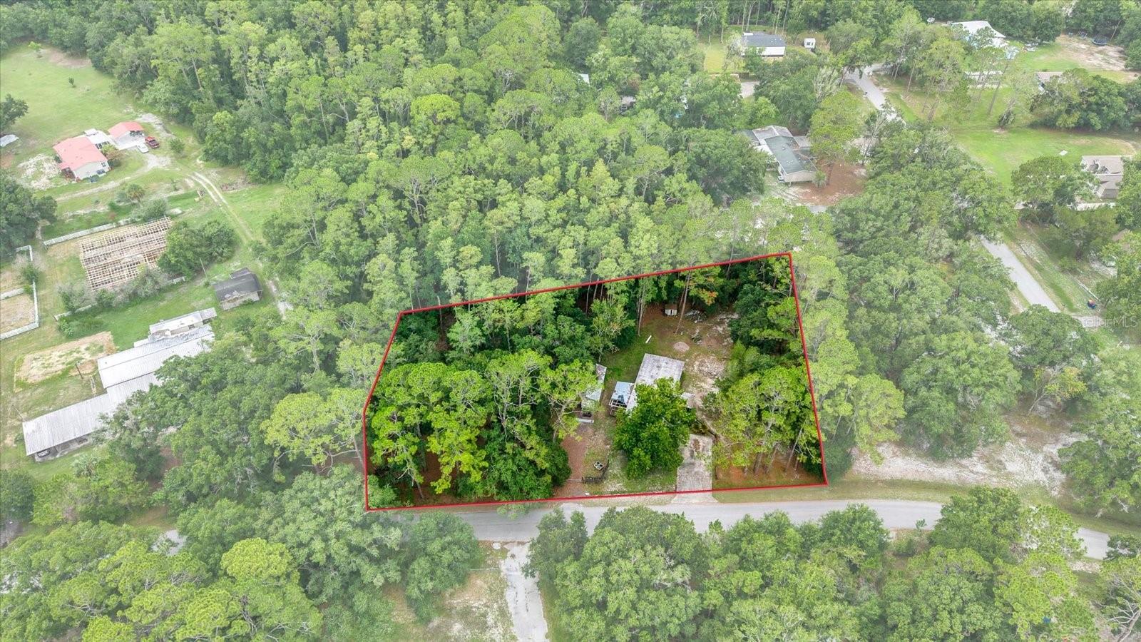 Discover the possibilities with this 1+ acre AR-zoned property in the heart of Wesley Chapel! Offering a rare combination of space, flexibility, and location, this property is ideal for investors, builders, or homebuyers looking to create a more private lifestyle without the restrictions of an HOA or CDD. A nicely paved road, 316 feet of frontage AND no deed restrictions and make this lot even more attractive.
The existing mobile home is being sold as-is and presents an opportunity for renovation or replacement, allowing the next owner to bring their vision to life. A detached carport provides excellent covered storage for an RV, boat, trailer, work vehicles, or outdoor equipment.
Enjoy the convenience of private well and septic, eliminating monthly water and sewer bills while providing added independence. The property is partially fenced and surrounded by mature pine trees, creating a peaceful setting with natural privacy. 
An existing homesite with well, septic, and utility connections may offer potential savings on future development costs. Buyers are encouraged to verify any impact fee credits or development benefits with the Pasco County Building Department.
Located just minutes from I-75, Tampa Premium Outlets, The Shops at Wiregrass, AdventHealth Wesley Chapel, top-rated restaurants, entertainment, and everyday conveniences, you'll enjoy the perfect balance of country-style living with city conveniences close by.
If you've been searching for acreage, privacy, and the freedom to make a property your own, this Wesley Chapel opportunity is one you won't want to miss