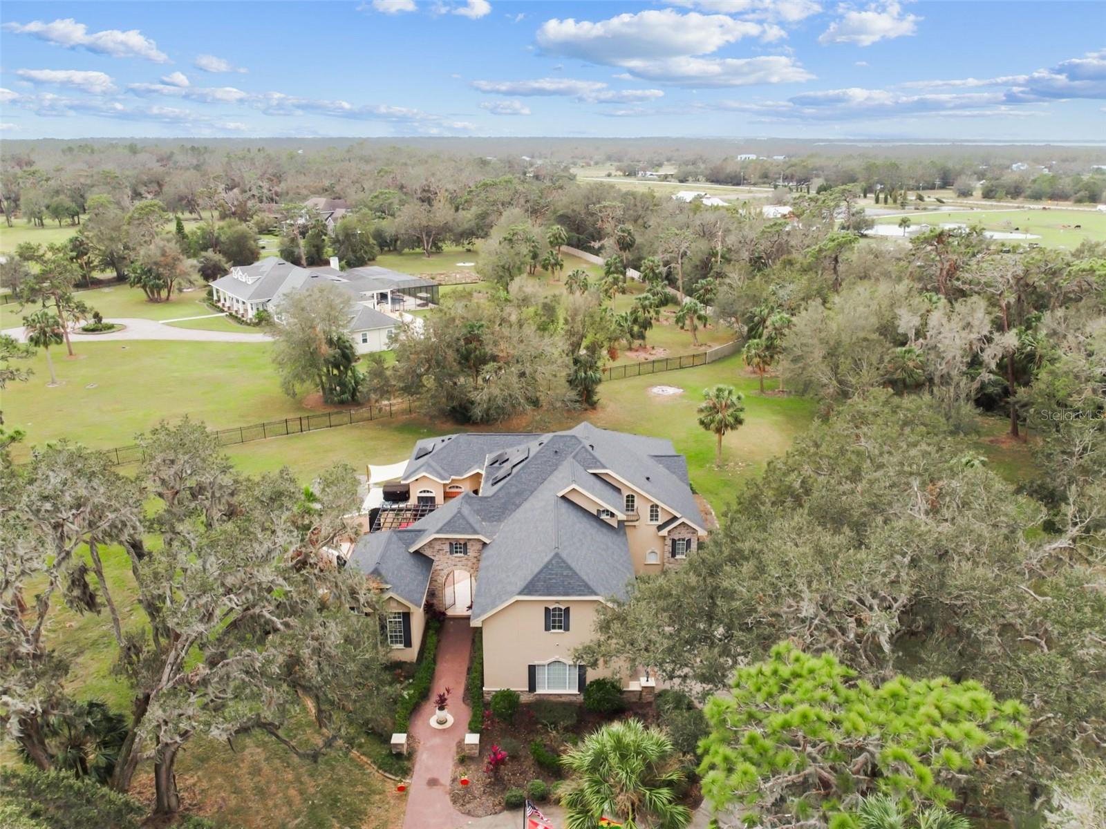 You have found your custom-built estate, where elegance, luxury, and attention to detail meet the charm and peace of rural living. Set on over 6 acres and surrounded by majestic 100-year-old oak trees, this Mediterranean inspired paradise offers both privacy and sophistication. Pass through the iron security gate and follow the winding 500-foot paved driveway to reach the home. Step inside through the impressive 10-foot mahogany archway entry, where you'll be greeted by 12-foot ceilings and beautifully designed and inspired spaces. This expansive residence includes 6 bedrooms and 4 full bathrooms. The attached but separate in-law suite, accessed through the courtyard, provides privacy for guests or multi-generational living. The gourmet kitchen is a chef's dream featuring: granite countertops, built-in range, gas range, oven, and microwave, two sinks, dual islands, a planning desk, 8X10 walk-in pantry, and a wine cellar. The executive master suite is a luxurious retreat with double doors, high ceilings, private sitting area, wet bar, doorless double walk-in shower, jacuzzi tub, separate vanities, and spacious his-and-hers closets. Outside the master suite you will find an office that has been converted to a nursery. Just off the spacious living room, there is an additional bedroom with direct access to the exterior. Upstairs, you'll find two more bedrooms with a Jack-and-Jill bath, plus an outdoor balcony overlooking the courtyard. The 39-foot theater room, equipped with a 110-inch screen, high-definition projector, wet bar, wine chiller, and refrigerator, is ideal for movie nights and gatherings. The stunning courtyard is the heart of this home, featuring an outdoor kitchen, custom cedar pergola, and wood-burning stone fireplace. The 36x36 two-story barn has enough space for six horse stalls and comes with a finished, carpeted, and air-conditioned upper level that has been utilized as an office and game room. Additional highlights include an outdoor J375 Jacuzzi, pickleball court, greenhouse with an aquaponics system, and endless opportunities for entertaining and relaxing. In addition to being zoned for horses, this property is literally seconds away from the Alafia State Park Equestrian Trail with 20 miles of horse trails, extremely popular mountain bike trails, and 7,000 acres of state park land. No HOA, no CDD, newer roof, and solar panels producing 2-3 MWh each month. Several weddings and receptions have also been held on this incredible estate easily accommodating 100 guests. This property is just as practical as it is stunning. Call today for your private tour.