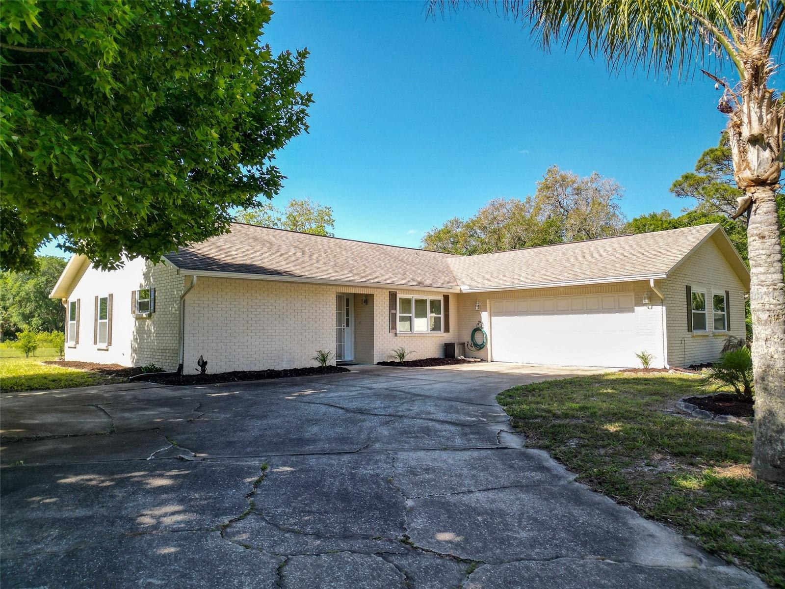 WOW! HUGE PRICE IMPROVEMENT! Experience the very best of country living on more than six private, fenced and cross fenced acres. Drive beneath majestic live oaks and swaying palms as you approach this great home, offering over 1,800 square feet of comfortable living space. Step inside to a light-filled living area featuring vaulted ceilings, a stunning wood-burning fireplace, and French doors that open to the fenced yard and expansive pasture beyond—perfect for blending indoor and outdoor living. The beautifully updated kitchen showcases rich wood cabinetry with beveled glass accents, granite countertops, and stainless-steel appliances. A central island and counter-height peninsula provide ample prep space, casual seating, and an ideal setup for entertaining. The cozy eat-in area is perfect for morning coffee or relaxed meals at home. Designed with privacy in mind, the split-bedroom floor plan includes three bedrooms and two bathrooms. The spacious primary suite offers a large walk-in closet, linen storage, and a private ensuite bath. Two additional bedrooms on the opposite side of the home feature ceiling fans and double closets, with an updated guest bath boasting a tiled shower and elevated vanity. Recent upgrades include impact windows throughout for added peace of mind. Enjoy the benefits of a private well with water treatment and softener system—no high city water bills here. Outdoors, a 12x24 metal shed provides plenty of space for storage, farm & yard equipment, or create the perfect workshop, man cave, or she-shed. Embrace the charm of Old Florida living—gentle breezes through Spanish moss, peaceful mornings filled with birds and butterflies, and the tranquility of your own private retreat. The mature landscape includes bottle brush, live oaks, young citrus trees, a variety of palms and a huge sweetgum tree for shade and shelter. Whether you're seeking space for equestrian pursuits, a hobby farm, or simply room to spread out, this lovingly maintained property offers endless possibilities. Situated just minutes from Mosquito Lagoon, renowned for spectacular redfish and shrimp harvests, and with easy access for boating, kayaking, and dolphin & manatee watching. An easy drive to Cape Canaveral, Kennedy Space Center, three airports and Central Florida theme parks & attractions. Come see it for yourself—your escape awaits!