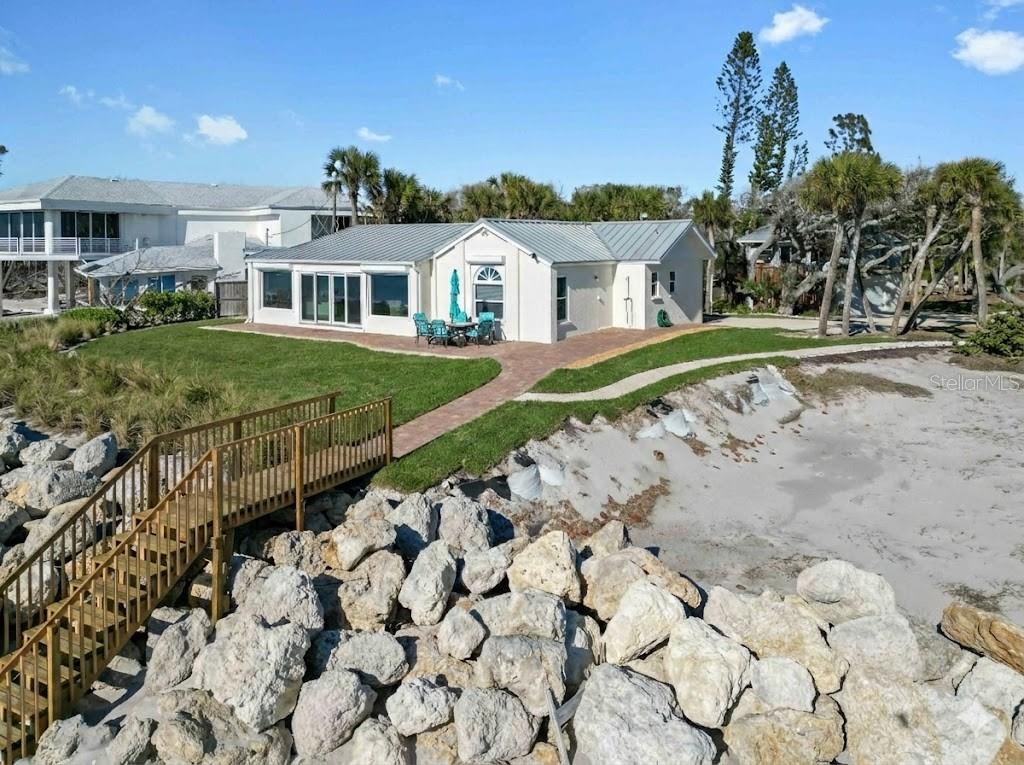 Premier Gulf-front gem on secluded Manasota Key, Englewood — where true privacy meets unbeatable coastal living. This rare 3-bedroom, 3.5-bath compound spans over 2,200 square feet on more than half an acre, with 100 feet of private beachfront directly on the Gulf of Mexico. The main residence offers two bedrooms and two-and-a-half baths, while a detached 576-square-foot guest suite above a two-car garage — complete with bedroom, full bath, kitchen, dining, and living areas — delivers total flexibility for guests, family, or rental income.
Step outside to your own front-row seat to sea turtles laying eggs and hatching during season — one of the rarest wildlife experiences anywhere. This stretch of beach is famous for shark teeth finds, including big Megalodon fossils. No crowds, no noise — just you and the water.
The elevated yard sits behind a large rock retention wall, providing serious storm protection and a commanding view of the Gulf. Brand-new sod, freshly built stairs, and new pavers throughout give the entire property a finished, move-in-ready feel. Inside, new impact windows, sliders, and a full irrigation system round out the upgrades — this home has been thoughtfully improved top to bottom.
A deeded dock slip across the street on Lemon Bay is perfect for calm launches, kayaking, or quick Gulf access. Seclusion, views, and waterfront ease — direct Gulf of Mexico frontage ideal for sunrises, barefoot walks, effortless boat rides, and legendary shelling on your own sand.
