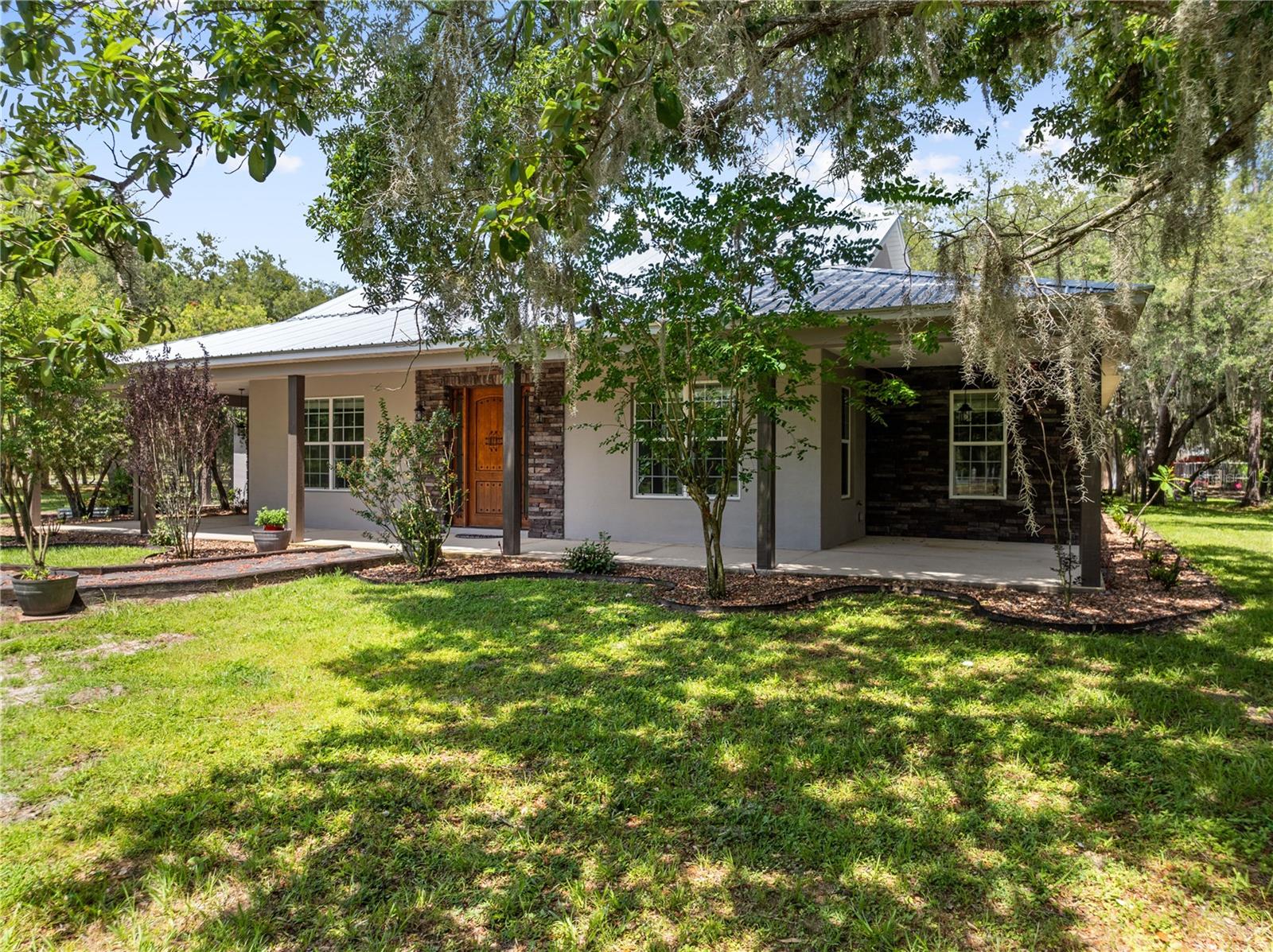 Virtually Staged. Tucked beneath mature oaks on 2.44 fenced acres, this custom property was built for buyers craving space, flexibility, and the freedom to live differently. Bring the RV, boat, trailers, chickens, hobbies, and toys, there’s room for all of it here. Centered around a screened saltwater courtyard pool and spa with outdoor shower, the home was designed for indoor-outdoor living with French doors opening to the courtyard from multiple rooms throughout the home. Inside, the 3.5 bath, 4 bedroom (could be 5) split floorplan offers multiple flexible living spaces, including a formal dining room, breakfast nook, family room, oversized great room/game room, and a front flex space ideal for a home office, bonus room, or additional living area. Rich wood cabinetry, quartz countertops, stainless appliances, gas cooktop with pot filler, double convection ovens, oversized island, stacked stone accent walls, and an Old World wood and iron entry door add warmth and character throughout the home.The 40x30 red iron building with electric, water, and 4 oversized roll-up doors easily accommodates RVs, boats, trailers, work vehicles, workshop needs, or recreational storage. The property also features horse stalls, chicken coop, fenced garden area with irrigation, whole-property irrigation, separate irrigation well, electric gate, covered front porch, concrete safe room with impact-proof glass window, new tankless water heaters, and new metal roof installed in 2025.Despite its peaceful country setting, the property is conveniently located just minutes from the Florida Turnpike and historic downtown St. Cloud, known for its lakefront, locally owned shops, coffee spots, restaurants, and small-town charm.
