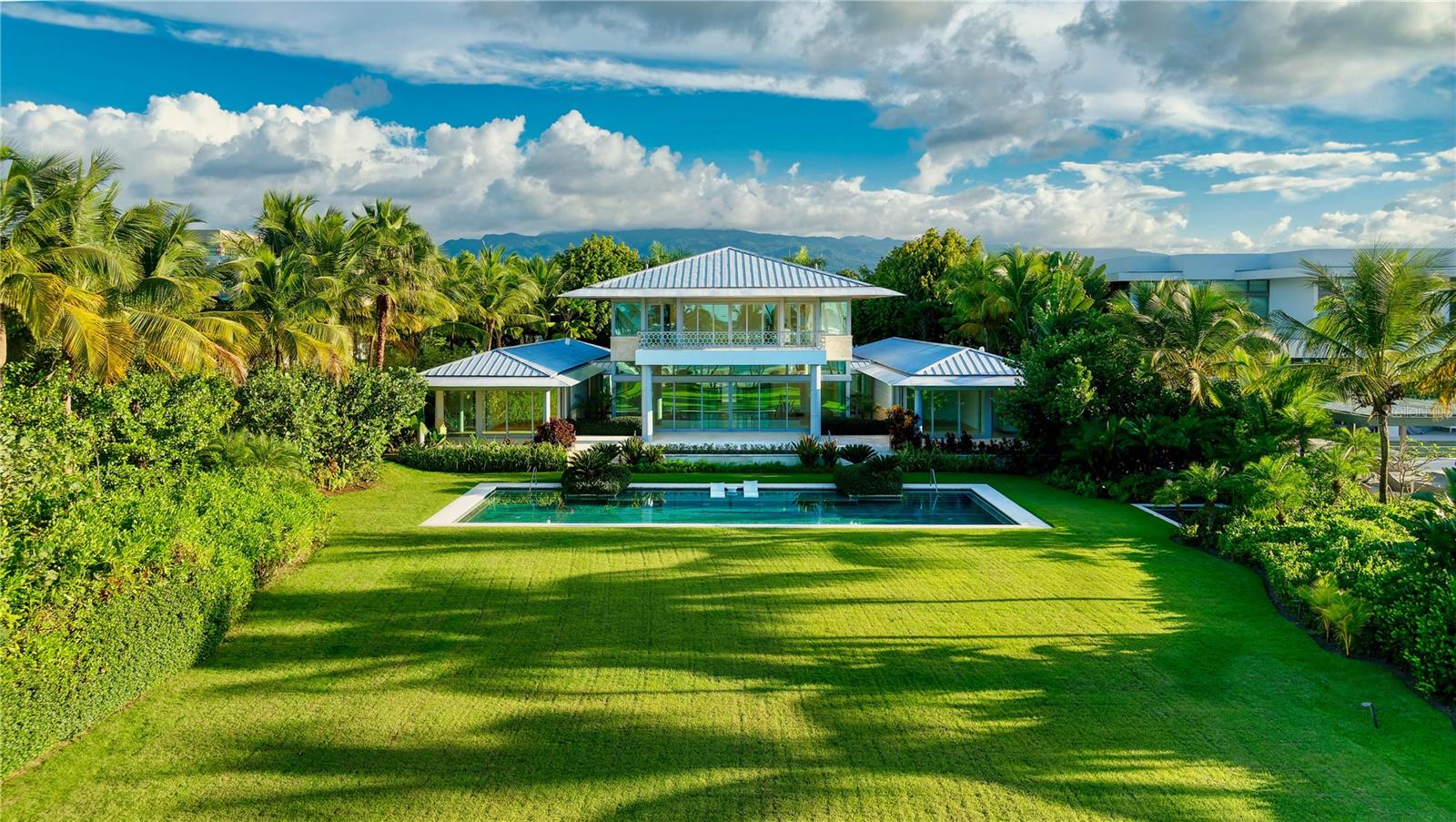 One or more photo(s) has been virtually staged. ***SOLD*** Set amidst lush tropical vegetation on just under 2 acres of mature landscaped terrain by the ocean. Within the prestigious Four Seasons Resort and Residences Puerto Rico in Rio Grande, an extraordinary retreat with state of the art security features. Experience the allure of a truly unique resort lifestyle within one of the most expansive beachfront estates in Puerto Rico, where your feet are nestled in the sand, bringing the beauty of the outdoors in. 12 Las Estancias is the largest lot on this exclusive street. Enjoying a prime location at the end of a quiet cul-de-sac flanked by a serene, secluded beach on one side and the 17th hole of the highly acclaimed Trent Jones Jr.-designed golf course with the magnificent Audubon International Nature Reserve beyond. This awe-inspiring compound consists of a main residence and 4 casitas. The main residence promises unparalleled luxury with every amenity a discerning homeowner could desire. Encompassing throughout the entire compound 11,000 interior Sq. Ft., 9 bedrooms, 10 full baths and 3 powder rooms, this oasis is shielded from view by lush landscaping; including a graceful archway of Hong Kong orchids. The estate was built by the owner to provide the best privacy and luxurious living a lifestyle can offer. The additional 4 properties include a wellness casita, and 3 well appointed casitas that provide for the utmost comfort and convenience for guests. Upon entry, you are greeted by a winding driveway framed by blooming flora and manicured landscaping revealing the main residence's grand double-height atrium with water features, leading to a great room bathed in natural light. The main residence's beautifully appointed primary suite encompasses the entirety of the second floor for the utmost privacy, showcasing breathtaking vistas from its expansive terrace overlooking the impressive 65-foot swimming pool and Atlantic Ocean. The suite is equipped with dual bathrooms, custom-built walk-in closets and private sitting room. Additionally, the main residence boasts two independent en-suite bedrooms on the first floor, along with an office, library and a media room. Outside, immerse yourself in the remarkable scenery from large terraces seamlessly connecting the interior spaces to the outdoor paradise. The expansive lawn stretches effortlessly towards a pristine two-mile beach haven, evoking the feeling of your own secluded oasis. The alfresco space is perfect for hosting and  large scale entertaining. The compound's 3 guest casitas, each with two en-suite bedrooms, living room, and kitchen, ensure all needs are catered to. The wellness casita was designed for serenity and rejuvenation in mind. Featuring a fitness center with ballet barre, sauna, massage room, bathroom, and a steam shower. Ready to move in, welcome to your dream retreat within the Four Seasons Resort and Residences Puerto Rico, a Five-Star, Five Diamond Resort and only Certified Gold Audubon Signature Sanctuary in the entire Caribbean. Access to tennis and pickleball courts, beach club with oceanfront pool, two miles of picturesque beaches, 70 acres of lakes and an 18-hole golf course designed by Trent Jones Jr. is enjoyed by residents. Near the Yunque National Rainforest, one of the island's most celebrated natural wonders. Photos 6 through 10, and 13 through 19 are virtually staged and do not reflect the current state of the property.