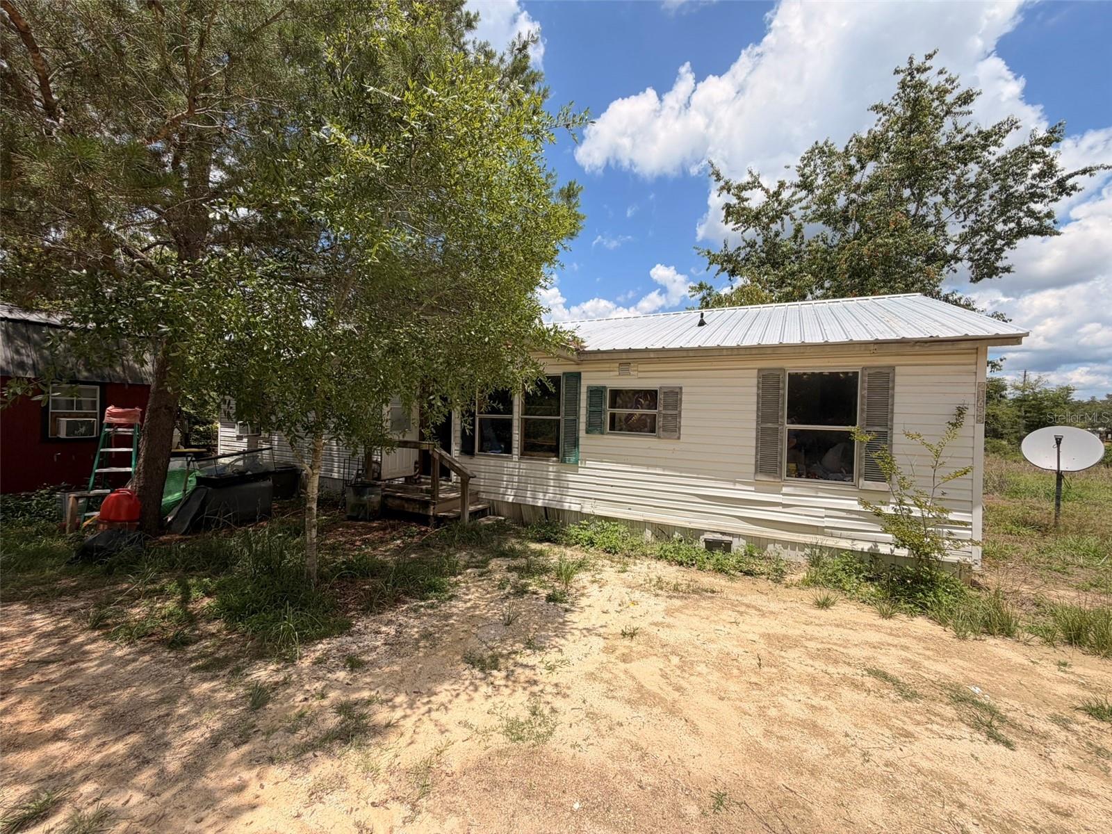 INVESTOR OPPORTUNITY!!! in Salt Springs with Lake Kerr access! Located in the Ocala National Forest and close to the Salt Springs Recreation Area, this spacious split-bedroom mobile home offers strong value-add potential on a generous lot. Features include a newer metal roof (installed approximately 2 years ago), separate kitchen, private primary suite, and two additional bedrooms with their own bathroom on the opposite side of the home. Property also includes a 50-amp RV hookup and detached 12x16 shed with window AC. Peaceful location near boating, trails, camping, and outdoor recreation. Property sold AS-IS. Seller has no information on well, septic, or HVAC.