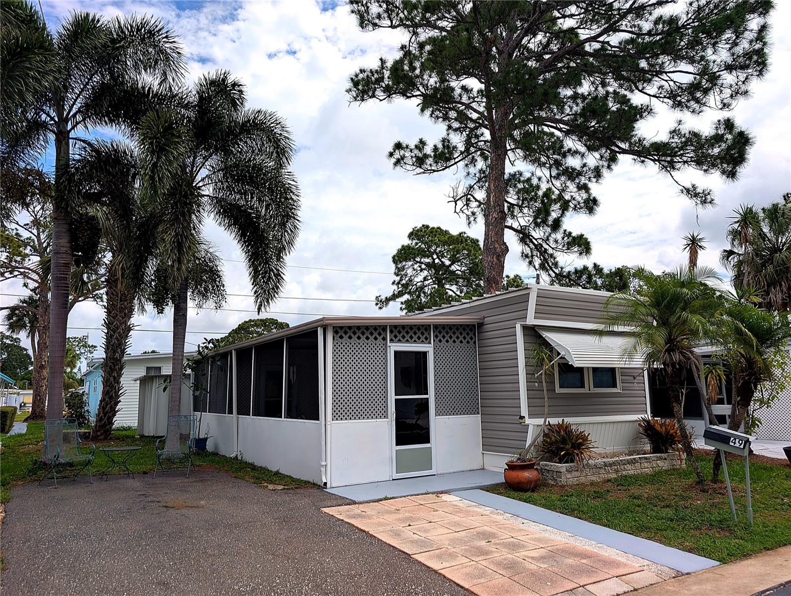 Move-in ready and full of charm, this updated 1 bed/1 bath home sits in Melody Gardens, a resident-owned 55+ community in St. Petersburg, and the share is included. Just short distance from the heated community pool and hot tub via a direct sidewalk to the clubhouse and recreation area, the location is hard to beat. Inside you'll find updated wood-look laminate flooring, a bright open living/kitchen/dining area, a refreshed bathroom with a walkin shower, and a fully equipped kitchen with refrigerator, smooth-top range, and microwave. Two window A/C units and an updated circuit-breaker electrical panel keep things comfortable, and the home's shaded setting under mature pines and palms helps keep it cooler year-round. Storage is exceptional, including a large screened lanai, an enclosed utility room with washer and dryer, and a separate exterior lockable storage closet. Fresh new vinyl siding wraps the home, and there is a roof-over with no leaks. The community shines with a heated pool and hot tub, fitness center, shuffleboard courts, and a clubhouse hosting dances, karaoke, darts, a bike club, and many holiday events. The low monthly HOA of only $195 includes water, trash, and lawn care. A rear gated entrance adds convenience, and the home is in flood zone X. Sold furnished or unfurnished. Minutes to the Bay Pines VA, the Pinellas Trail, and nearby shopping. Buyer approval by the community is required.