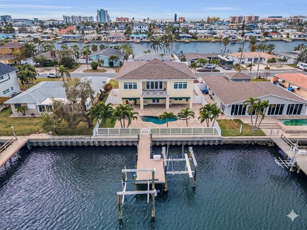 A BOATER’S PARADISE MEETS SUPERIOR, HIGH-QUALITY COASTAL CONSTRUCTION.  Welcome to a “built-to-last” waterfront sanctuary!  Elevated with all block construction and poured concrete floors, you’ll appreciate the peace of mind offered by this exceptional, easy living waterfront residence.  A spacious brick paver driveway, generous 6-car garage parking, and two 10,000 lb boat lifts make this the perfect place for your vehicles and watercraft.  Driftwood-style porcelain floors, lovely crown woodworking and tall 10ft-high ceilings introduce a wonderful open floorplan with beautiful views of the waterfront.  Your spacious living room opens to an elegant 225sqft covered balcony with a built-in electronic sunshade.  Fabulous chef’s kitchen boasts fine quartz counters/backsplash, rich coastal cabinetry, huge wrap-around multi-level breakfast bar, under and above cabinet lighting, and pantry closet.  Double doors open to a fabulous waterfront owner’s suite that opens to the waterfront balcony and features two walk-in closets with built-in dressers.  Owner’s bath provides dual quartz vanities and an exquisite designer walk-in shower with seating bench. Second bedroom is oversized and en suite, and has a graceful bath with jetted tub and shower. Third bedroom is spacious and has a walk-in closet with adjacent full guest bath.  Your private backyard oasis awaits you!  Discover a huge 470sqft covered deck that transitions to a large paver area with a gorgeous Pebbletech Pool/Spa.  Deck offers lots of lounging space and covered outdoor dining.  Updated seawall supports a composite dock with two boat lifts.  Bahamian shutters on the outside, plantation shutters on the inside, large and well-finished laundry room with extensive cabinetry storage, lower-level multi-purpose area, large 8ft-high elevator, PVC privacy fencing, and so much more.  Located within easy walking distance of the powder soft sands of Treasure Island beach, dining, shopping and entertainment.  An outstanding value in an excellent waterfront boating community!