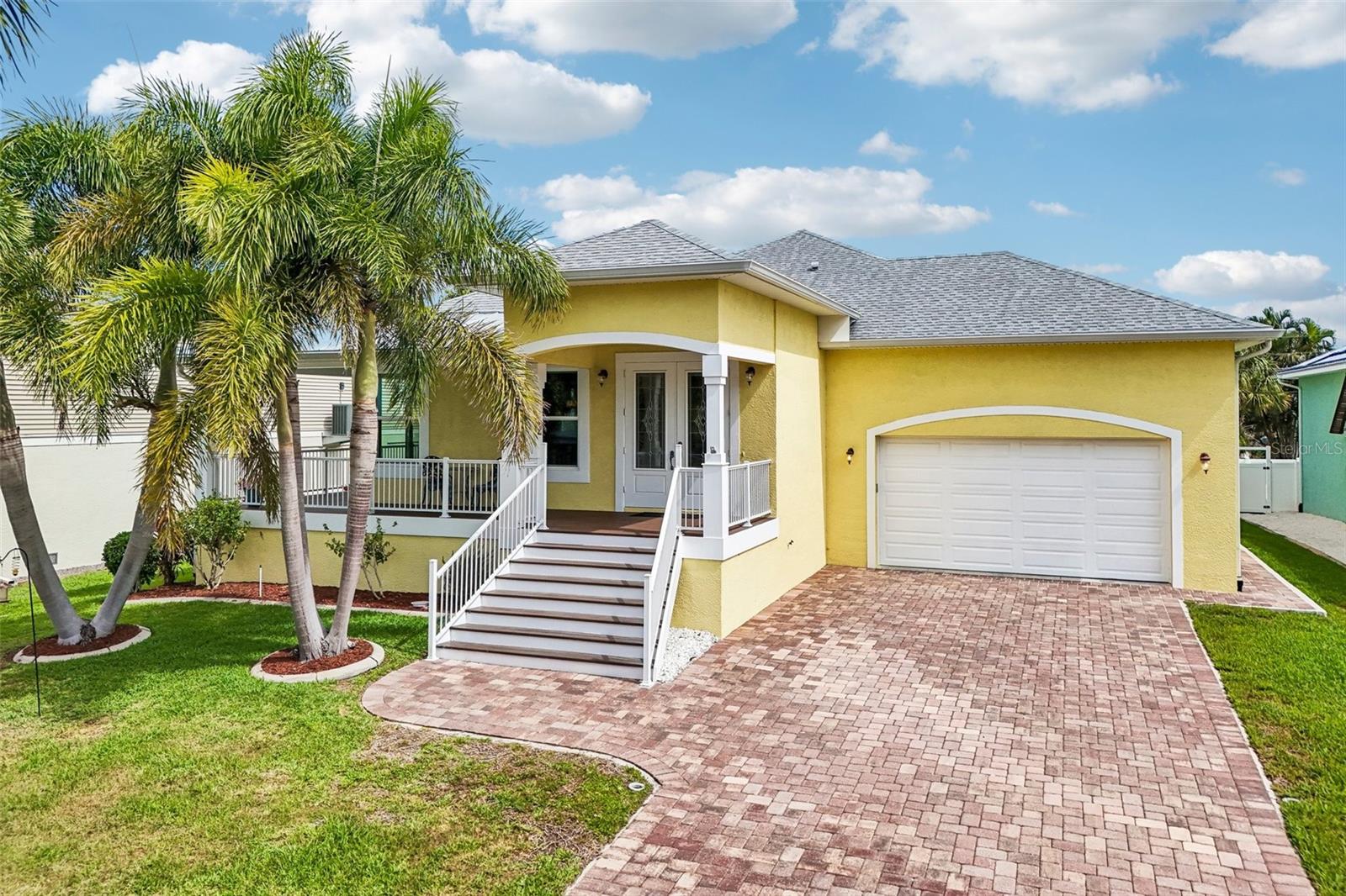 Elevated Coastal Living, Prime Location Near Palma Sola Bay & Minutes to Anna Maria Island Tucked into the sought-after Palma Sola area of Northwest Bradenton, this elevated 2016 home places the best of West Bradenton coastal living just moments from your door. Set near Rose Park, Palma Sola Bay, waterfront parks, nearby boating access & the neighborhood charm that makes this area so special, the location offers the rare feeling of being close to the water while still keeping everyday convenience within easy reach. A welcoming front staircase leads to a wraparound porch with Trex enhanced decking, powder-coated aluminum railings & a coastal blue ceiling, creating a low-maintenance outdoor living space perfect for morning coffee, evening conversations or relaxing after time spent near the bay. With its elevated design, paver driveway, tropical landscaping & inviting coastal character, the home makes a memorable first impression from the moment you arrive. Inside, the home opens to a bright and polished living space filled with thoughtful details & custom finishes. Real wood floors flow through the main living areas, while crown molding, recessed lighting& detailed ceiling treatments add warmth & architectural interest throughout. The living room features a striking coffered ceiling with contrasting inset detail, creating a beautiful focal point above the main gathering space. Large windows and sliding glass doors bring in natural light and extend the living area out to the wraparound porch, giving the home an easy connection between indoor comfort and outdoor living. The kitchen is both functional and refined, offering tall cabinetry, quartz countertops, decorative backsplash, island seating, under-cabinet lighting, built-in wall oven and microwave, cooktop, pantry storage and a beverage/wine fridge area. The open layout keeps the kitchen connected to the dining and living areas, making it easy to entertain or enjoy everyday life without feeling separated from the rest of the home. The spacious primary suite continues the custom feel with tray ceiling detail, crown molding, porch access, soft natural light and separate his-and-hers walk-in closets, including an oversized closet with exceptional storage. The primary bath offers an upgraded retreat with a dual vanity, quartz counters and a large walk-in tile shower with frameless glass, bench seating, niche detail and handheld shower feature. Each additional bedroom includes its own walk-in closet, giving the home excellent storage throughout. Additional counters throughout the home feature Grade 1 granite, adding to the home’s thoughtful finish. Built w/ comfort, efficiency and convenience in mind, the home includes hurricane windows & doors, spray foam roof insulation, central vacuum & a 240V garage hookup ready for an electric vehicle charger. The attached garage & lower-level storage provide useful space for parking, tools, beach gear, bikes & the extras that come with living near the water. From here, you are just a short drive to the world-renowned beaches of Anna Maria Island, known for its sugar-sand shoreline, turquoise Gulf waters & unforgettable sunsets. Robinson Preserve, De Soto National Memorial, Neal Preserve, local marinas, boat ramps, cafés, shopping, medical offices & everyday conveniences are also close by. With no HOA restrictions, a desirable coastal setting & a newer elevated design, this home offers a rare blend of modern comfort, coastal charm & a prime location!