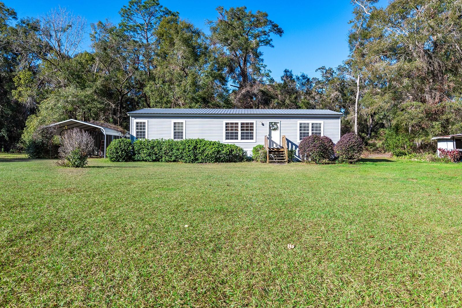 Nestled in the quiet countryside of Newberry, this charming 2-bedroom, 2-bath manufactured home offers the perfect combination of comfort, privacy, and country living. Situated on 10 beautiful acres, this property provides plenty of room to spread out and enjoy the peaceful surroundings while still being conveniently located near local amenities, schools, and outdoor recreation. Inside, the home features an inviting open-concept layout with a spacious living area, a functional kitchen with abundant cabinet storage, and a dining space ideal for everyday living or entertaining guests. The primary suite includes a private ensuite bath, while the additional bedroom offers flexibility for family, visitors, or the potential to create a third bedroom, home office, or hobby space. Step outside and take in all this property has to offer. A covered parking area and storage container provide added convenience, while the expansive acreage opens the door to endless possibilities including gardening, farming, recreational use, or simply enjoying the natural beauty and privacy of your own land. Mature trees and wide-open spaces create a serene setting that truly captures the charm of rural Florida living. Whether you’re searching for a peaceful homestead, a weekend retreat, or a property with room to grow, this Newberry gem is full of potential and ready to welcome you home.