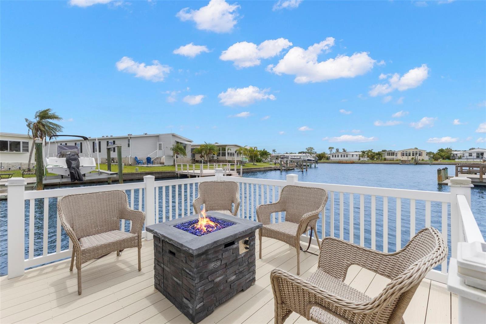 OFFERING DIRECT ACCESS TO TAMPA BAY and the ultimate Florida boating lifestyle, this beautifully maintained 2 BR/2 BA home is located in the highly desirable AMERICANA COVE, a gated 55+ community in St Petersburg.  Sitting 9 ft above sea level this home is situated on a peaceful canal and has many updates, Roof (2025), HVAC (2022), Dock & Lift (2024), and a water purification system to mention just a few.  Appliances include a Stainless-Steel LG gas stove (2 yrs old), Microwave (vented outside), and Stainless-Steel refrigerator with party drawer.  The large gourmet kitchen is adjacent to the large Dining Room with plenty of room to entertain family and friends.  The separate living room overlooks the waterfront and has access to the screened (15 X 15) lanai with composite decking and pull-down waterproof shades.  Step outside and enjoy morning coffee, breathtaking sunrises, and frequent visits from dolphins, manatees, and native birds from the 16 X 8 fenced Balcony separate from the lanai, A great place for gardening also. Beneath the lanai is an additional 15 X 15 storage area - no shortage of storage here!! The large Master bedroom has an ensuite bath with walk-in shower and enormous closet.  The 2nd bedroom has a sofa bed and TV and can easily be used as an office as well as for overnight guests.  The guest bath has a tub with shower, conveniently located across from the guest room, and has a laundry closet with washer and dryer.  The home has a large carport (30 X 30) for 2 cars plus a golf cart and includes a sizable shed with work bench and a loft for all your seasonal decor. Enjoy this active community with many activities and clubs.  The low $410 HOA includes water, sewer, trash pickup, and lawn mowing/edging, heated pool, fitness room, club house, shuffle, bocce, boat launch/marina and fishing pier, and access to Tampa Bay. Community is 10 minutes to downtown St Petersburg, 15 minutes to 2 airports and 20 minutes from the beaches. This is community living at its finest!  Check it out!!