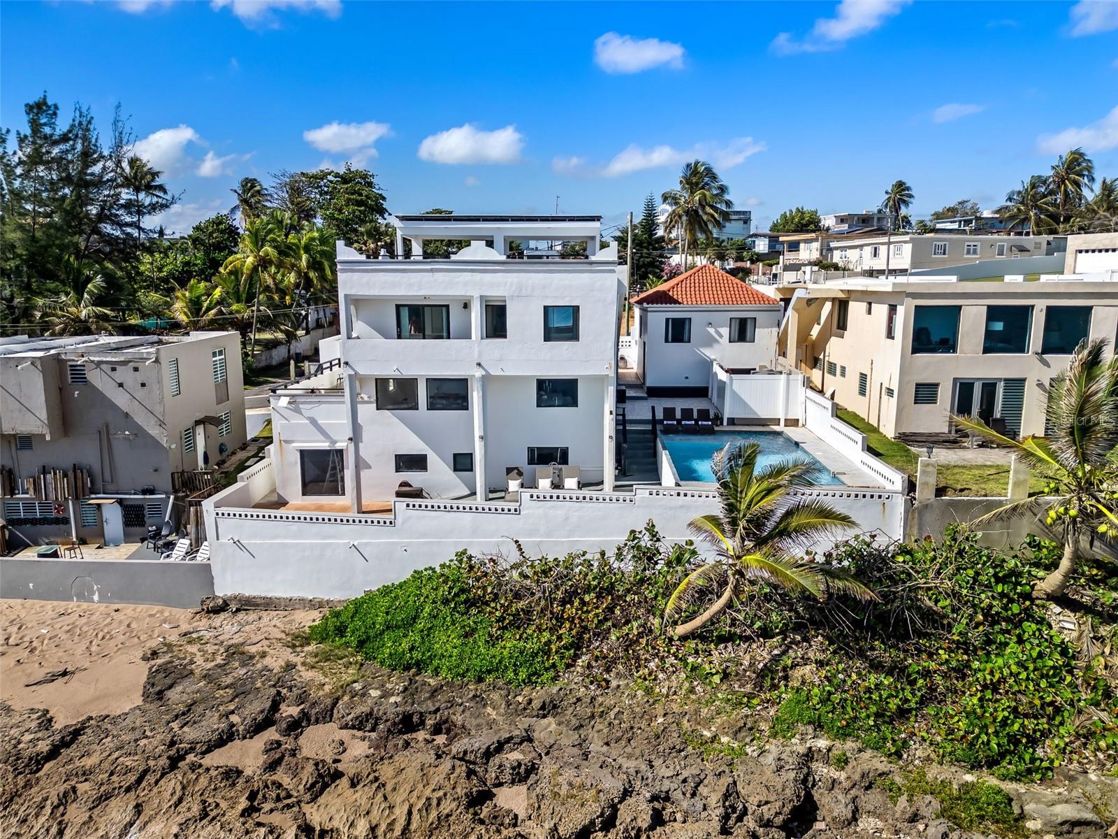 Rare oceanfront investment in Dorado: a turnkey, 5,200 sq.ft., multifamily estate on a 412 sqm lot. Located next to a premier surfing beach with unobstructed ocean views, this three-unit property is optimized for high-yield short-term rentals or a private family compound.
Property Highlights:
Main Residence: 4 BR / 3 BA with a panoramic rooftop terrace.
Studio Unit: Private 1 BR / 1 BA with full kitchen.
Apartment: 2 BR / 2 BA for additional rental income.
Amenities: Heated oceanfront saltwater pool, covered roof top terrace, solar panels with battery backup, garage, STR permitted and a 650-gallon water cistern.
Offered fully furnished and resiliently equipped, this versatile asset is ready for immediate operation in Puerto Rico’s competitive vacation market. No HOA
