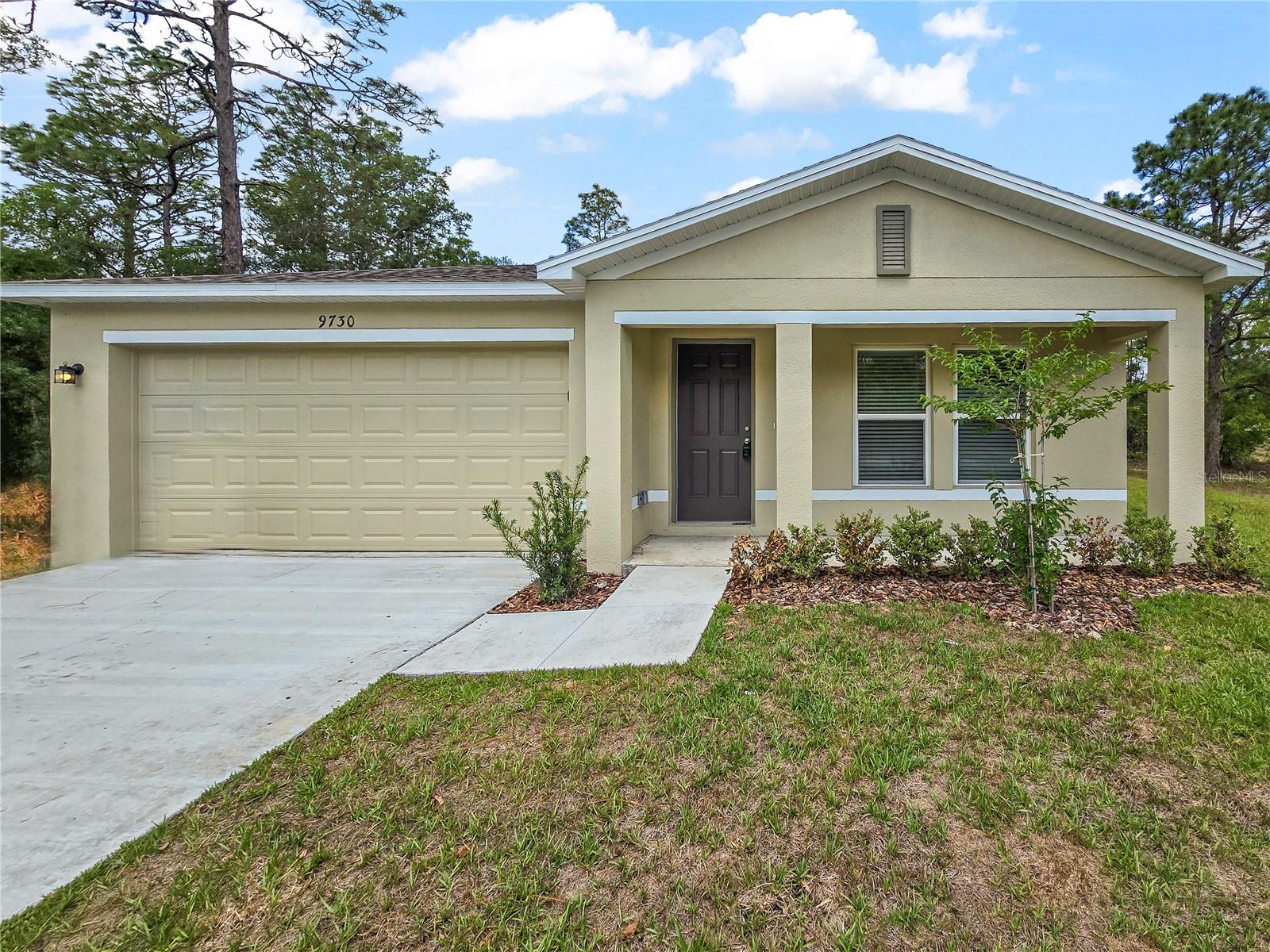 This beautiful new construction home features 4 bedrooms and 2 bathrooms across a spacious and thoughtfully designed 1,672 square feet of living space. Located at 9730 N Elkcam Blvd in the serene community of Citrus Springs, FL, this residence offers a perfect blend of modern style and functional comfort. As you step inside, you are greeted by an expansive open-concept great room that flows seamlessly into the dining area and a contemporary kitchen, ideal for daily living and easy movement. The kitchen boasting sleek white cabinetry, granite countertops, stainless steel appliances, and a convenient breakfast bar for casual morning meals. The interior is finished with stylish, durable wood-look flooring and a neutral color palette that complements the abundance of natural light streaming through the large windows. Retreat to the private owners suite, which includes a generous walk-in closet and an en-suite bath featuring dual vanities. Outside, the property includes a two-car garage and a covered patio area perfect for enjoying the peaceful Florida weather. Situated in Citrus County, this home provides a wonderful opportunity to enjoy a brand-new space in a growing and vibrant neighborhood. Disclosure: Some images have been virtually staged to better showcase the true potential of rooms and spaces in the home