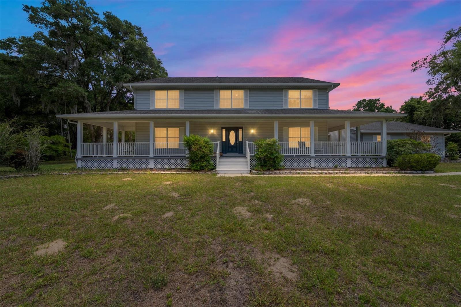 COMMERCIAL/AGRICULTURAL OPPORTUNITY. Situated on 10 private acres in Summerfield, just minutes from The Villages, this exceptional gated estate offers the perfect blend of luxury living, multi-generational flexibility, and equestrian-ready acreage. A long, paved driveway welcomes you into a true family compound designed for those seeking space, privacy, and versatility for both lifestyle and business needs. For car enthusiasts, business owners, or hobbyists, the property is equipped with a 10+ car garage capacity and multiple outbuildings. The impressive 1600+/- square foot of AC space in the workshop and total 4600+ square foot enclosed steel building includes a fully insulated expansion, offering enhanced usability along with three dedicated office spaces—ideal for running a business from home, storing equipment, or creating a private studio environment. Additional features include RV and boat storage, roll-up access, and covered parking.

The residence has been thoughtfully enhanced with the addition of a primary suite on the first floor, providing convenience and privacy with a beautifully appointed ensuite bath. Several bathrooms throughout the home have been recently updated with elegant marble tile finishes, elevating the overall design with a refined, modern touch.

Inside, the home features 4 bedrooms, 3 full baths, and a half bath, highlighted by a grand foyer, soaring two-story ceilings, and a spacious living area centered around a wood-burning fireplace. The gourmet kitchen is designed to impress with high-end appliances, a large center island, and both casual and formal dining spaces, making it ideal for entertaining and everyday living. A bonus room on the main level offers flexibility for a den, office, or media space.

Upstairs, additional bedrooms and living areas provide separation and comfort for guests or family, while the original loft-style primary retreat remains a unique feature with expansive closet space and a spa-like bath.

Outdoor living is equally impressive, with a wraparound porch overlooking the expansive grounds, mature landscaping, paver walkways, and multiple storage structures. The property is well-equipped with extensive parking, security lighting, and functional infrastructure to support a variety of uses, including equestrian pursuits—bring your horses and enjoy the open acreage.

Additional highlights include Andersen double-pane windows, crown molding, wood and tile flooring, a detached two-car garage with epoxy floors, an oversized laundry room, and additional flex spaces including a “she-shed.” The property is also offered with a home warranty and termite bond for added peace of mind.

Located within close proximity to shopping, dining, medical facilities, and entertainment, while still offering the privacy of acreage living, this is a rare opportunity to own a versatile estate in one of Central Florida’s most desirable and growing areas.