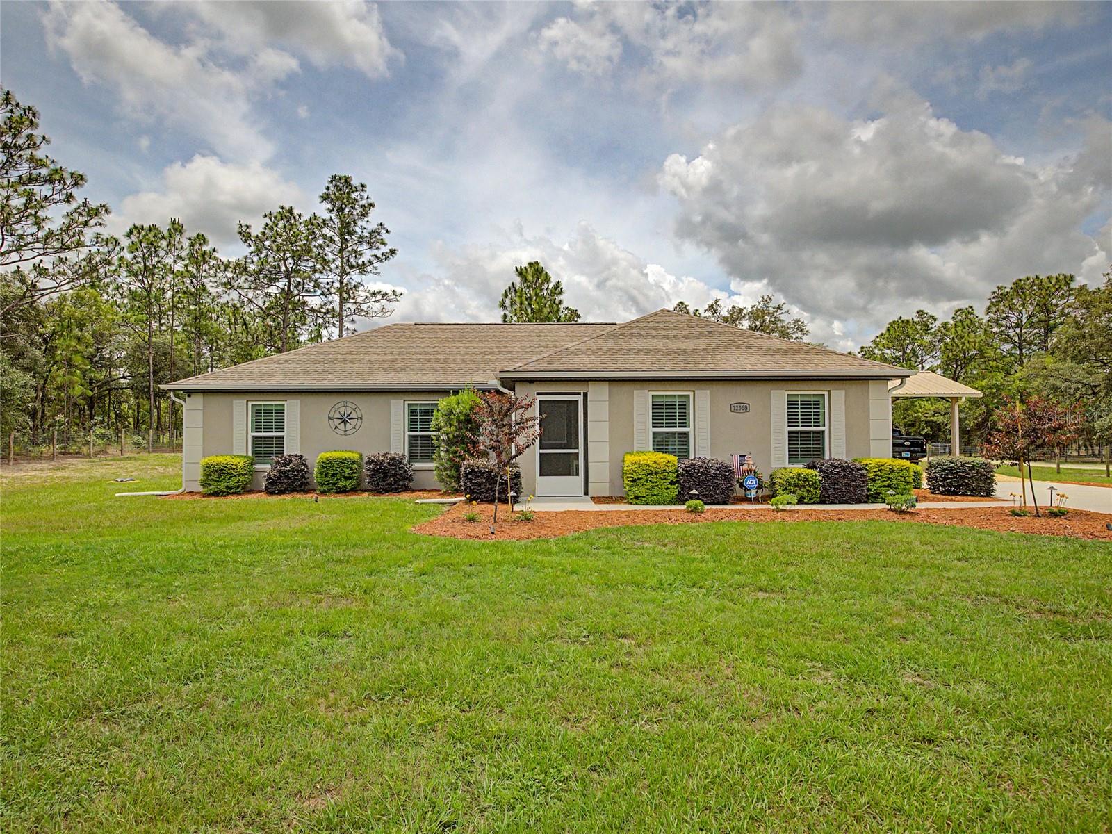 Extras!  Extras!  Extras!  Built in 2022 and situated on a spacious 1-acre corner lot in the highly desirable Rolling Hills community, this beautifully maintained 5-bedroom, 2-bath home offers the perfect combination of modern comfort, privacy, and functionality — all with no HOA! Featuring an open-concept layout, split-bedroom floor plan, high ceilings, and abundant natural light, this home was thoughtfully designed for both everyday living and entertaining.
The kitchen is the heart of the home, showcasing granite countertops, modern cabinetry, and a large center island overlooking the living and dining areas. Luxury vinyl plank flooring flows through the main living spaces with comfortable carpeting in the bedrooms. Plantation shutters add timeless style throughout the home.
Step outside and enjoy true Florida living with a screened entryway and spacious screened lanai overlooking the beautifully maintained property. The fully fenced yard includes a Ghost solar-powered gate system, offering added convenience, privacy, and security. Additional exterior features include gutters on the home, outbuilding, and the pole barn.  The pole barn offers under roof parking with electric and the   20x20 outbuilding with electric is perfect for storage, hobbies, workshop space, recreational equipment, or outdoor toys.
This property is also loaded with valuable upgrades for peace of mind and efficiency, including a whole-house 22kW generator with a 250-gallon underground propane tank, water filtration system with UV light, Blink security system, and ADT alarm system. With plenty of room for pets, RVs, future pool plans, and outdoor enjoyment, this move-in ready property offers the ideal blend of country living and modern convenience.
Conveniently located just minutes from SR 200, shopping, dining, medical facilities, the World Equestrian Center, Rainbow Springs, the Rainbow River, and Dunnellon, this exceptional property offers the lifestyle so many buyers are searching for in Marion County.