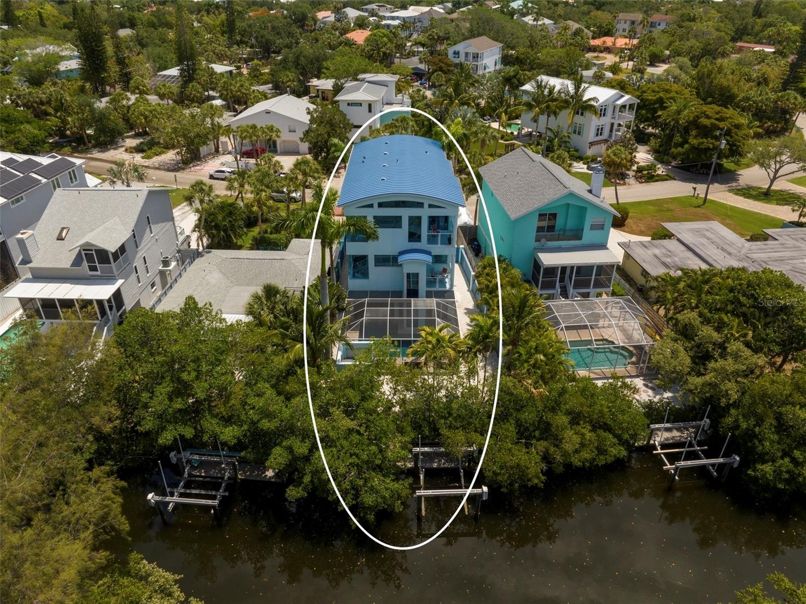 On beautiful Palm Island in the heart of Siesta Key and just 2 blocks from world famous Siesta Key Beach, you'll find this spectacular contemporary retreat with 4 bedrooms, 3.5 baths, designer finishes, incredible pool/lanai/summer kitchen, and private elevator, located on a great canal front lot with dock and lift for your boat. Sold turnkey furnished for your convenience, purchase as your own full or part-time home or use as an investment property with great rental income. The first level features an indoor/outdoor swimming pool and spa, screened-in lounge area and full outdoor kitchen with stainless appliances and gas range making it the perfect place for family fun and entertaining. The main living space features a spacious commercial grade chef's kitchen with imported cobalt blue, Italian Lube cabinetry, 4-burner gas range, stainless appliances, bar style dining, and upgrades including pendant lighting, wine refrigerator and convenient pot filler. The 2-story living room boasts a soaring ceiling and custom designed stained-glass windows by Schumann Glass Art with carvings simulating the movement of water in a fantastic color spectrum. The space also includes screened terrace access, and electric fireplace that creates a relaxing ambiance. Relax in the private owner's suite bathed in light through the glass block wall feature and luxuriate in the owner's spa-like bath with tub and shower, gorgeous granite counters, etched glass, and Toto toilet system. Upstairs you'll find 3 spacious bedrooms and 2 full baths, and a bonus loft space and terrace with great sunset views. 2 laundry rooms are conveniently located on the second and third floors. Floors in the residence are polished white travertine, white oak plank & coquina style brick. All windows and doors are impact. The screened lanai is a master class in the Florida lifestyle; enjoy your heated pool and spa surrounded by tropical plantings and a view towards the canal. From your dock with boat lift, explore the sparkling waterways of Florida's Gulf Coast with easy access to the Grand Canal and Sarasota Bay. Generous 2 car garage with extra space for storage and paver driveway with ample parking. Great location just a short distance to cafes and shops in the nearby bustling Siesta Key village, and close to shopping, restaurants, hospitals and the many cultural activities in Downtown Sarasota. World-class living on many levels, Siesta Key is home to the #1 beach in the nation.