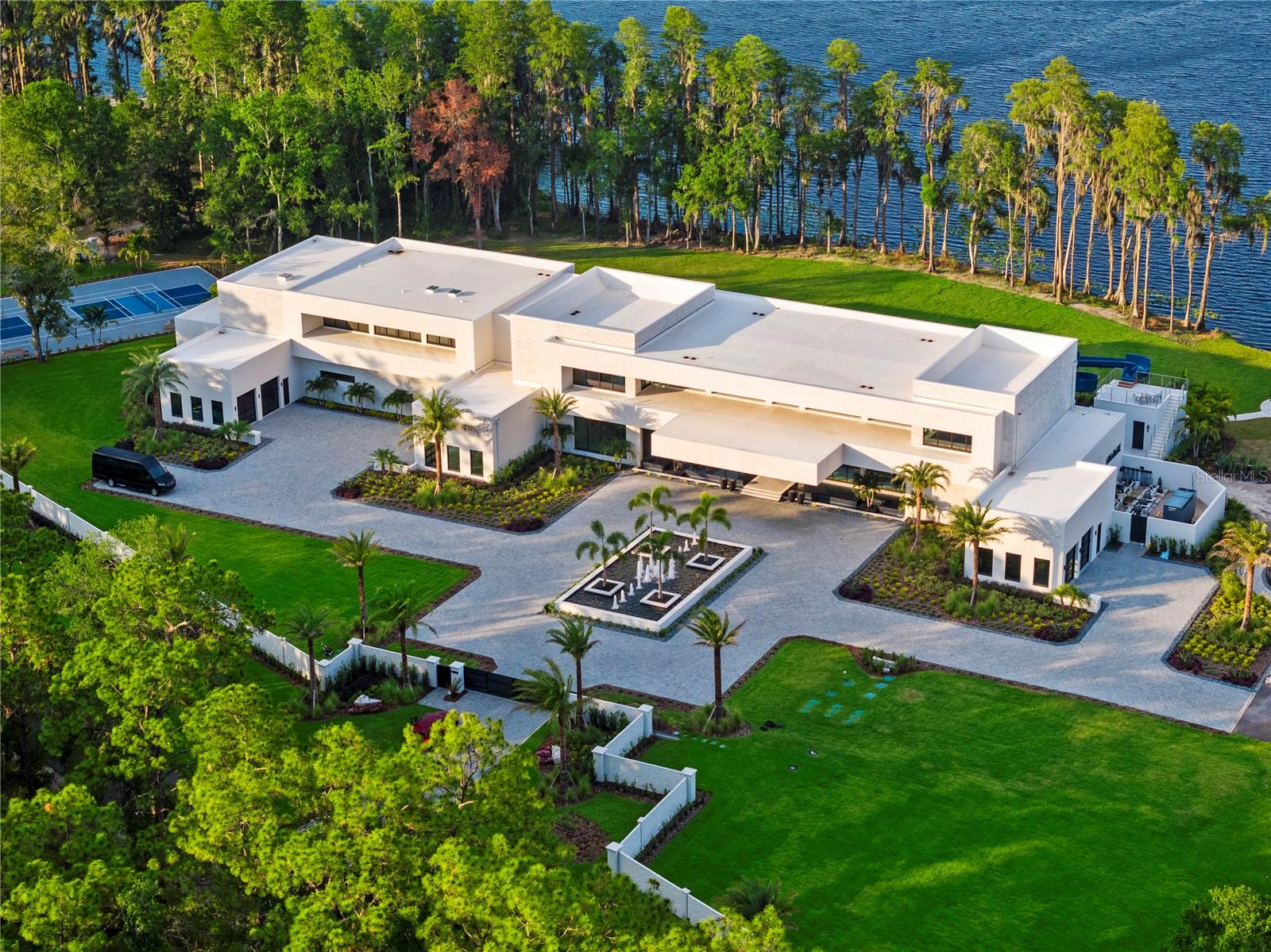 Welcome to a truly one-of-a-kind, ultra-luxurious estate that embodies the pinnacle of modern design and sustainable living. This newly built (2024), resort-style masterpiece by renowned architect Phil Kean showcases unparalleled craftsmanship and meticulous attention to detail, with no expense spared in every aspect of the home. This architectural sanctuary is set on a breathtaking nearly 5-acre lakefront homesite with expansive views of the private Island Ford Lake. The show-stopping multi-million dollar infinity pool, designed by Ryan Hughes and featured on the cover of Luxury Pool & Outdoor Living Magazine, is just the beginning. With a tennis court, pickleball court, and dock equipped with boat and jet ski lifts, this estate offers a true waterfront lifestyle. The covered lanai is nearly 4200 SF alone and features an automatic remote screen and full outdoor pool bath. Inside, you’ll discover an impressive movie theater, with a state-of-the-art sound system, captivating audio-visual, and lighting features throughout the home. The main residence boasts expansive living areas, 5 bedrooms, 7 bathrooms, and over 13,000 SF of living space, with a total of nearly 23,000 SF. The estate's total includes 6 bedrooms, 10 bathrooms, and features a total of 6-car garage bays with high ceilings, allowing for car lifts. Guests will enjoy a luxurious ADA-accessible 1-bedroom, 1.5-bath guest house, while the charming lake house cabin includes a full kitchen, bath, and screened porch for relaxing after a day on the water. For wellness and relaxation, the estate offers a state-of-the-art sauna room, a tranquil massage room, and a fully equipped fitness center, ensuring every need for rejuvenation and physical well-being is met. This home is enhanced with world-renowned Alex Turco art, which wraps the inside and outside bar as well as the pool water feature. The estate is fully enclosed by a stone wall for ultimate privacy and security, with gate access featuring facial recognition at the main entry and a separate service entrance. With too many features to list, this sanctuary offers the tranquility of lakeside living, just moments away from the vibrant Tampa Bay area.