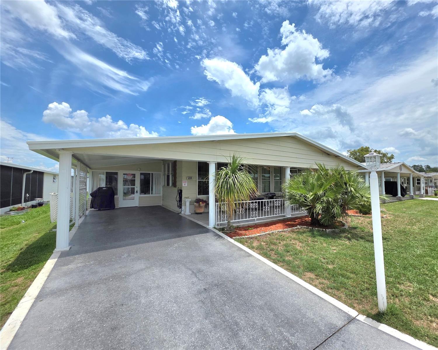 Charming Doublewide Home with Expansive Living Space in the Betmar Acres Community. Discover the perfect blend of comfort and style in this spacious home, offering a total of 2,936 square feet of generously designed living space, ideal for those seeking the perfect retreat in sunny central Florida. 2 spacious bedrooms and 2 full bathrooms, make this home perfect for guests or family. Enjoy the fresh air on your 10'x34' covered front porch, inviting raised screen room, or the street-level Florida room which features a breezeway, ceiling fan, and tile floors. An attached 10'x32' utility/laundry/workshop includes wall AC and convenient double doors for parking the included Club Car golf cart. A stylish entry foyer with tile flooring and a storage closet leads you into the heart of the home where the centrally located kitchen impresses with a cathedral ceiling, built-in bookshelves, a cooking island with a vent hood, breakfast bar seating, double wall ovens, closet pantry, dishwasher, garbage disposal, and a side-by-side refrigerator/freezer. The formal dining area features a built-in hutch for storage and sliding glass doors that seamlessly transition to a bonus room with portable AC, currently set up as a guest sleeping area but easily adaptable for various uses. The expansive front living room boasts stunning floor-to-ceiling windows, built-in bookshelves, laminate flooring, a ceiling fan, and access to the raised screen porch for perfect indoor/outdoor living. The guest bedroom connects to a Jack & Jill style full bathroom, while the primary suite provides a luxurious retreat with a cathedral ceiling, a walk-in closet, and an en-suite bathroom featuring double sinks and a recently updated XL walk-in shower. Notable exterior features include a beautifully landscaped yard, gas grill, accessible ramp to the porch, durable aluminum lap siding, rubber and metal roof, gutters, a rain barrel, and a rear patio with a roll-up awning enhance the outdoor experience. Additionally, the home boasts an updated HVAC system (new in July 2025) and transferable termite protection until February 2027. Fully Furnished & move in ready. Located in Betmar Acres, one of central Florida’s most desirable 55+ communities where you own your land and can enjoy a wide array of activities including Bingo, shuffleboard, swimming in the pools, relaxing in hot tubs, playing golf, or engaging in pickleball—all designed to keep you entertained and active in the sunshine state. Plan Your Visit Today! Don’t miss out on this opportunity to own a slice of paradise in a vibrant community. Schedule your tour and experience the lifestyle that awaits you in Betmar Acres!