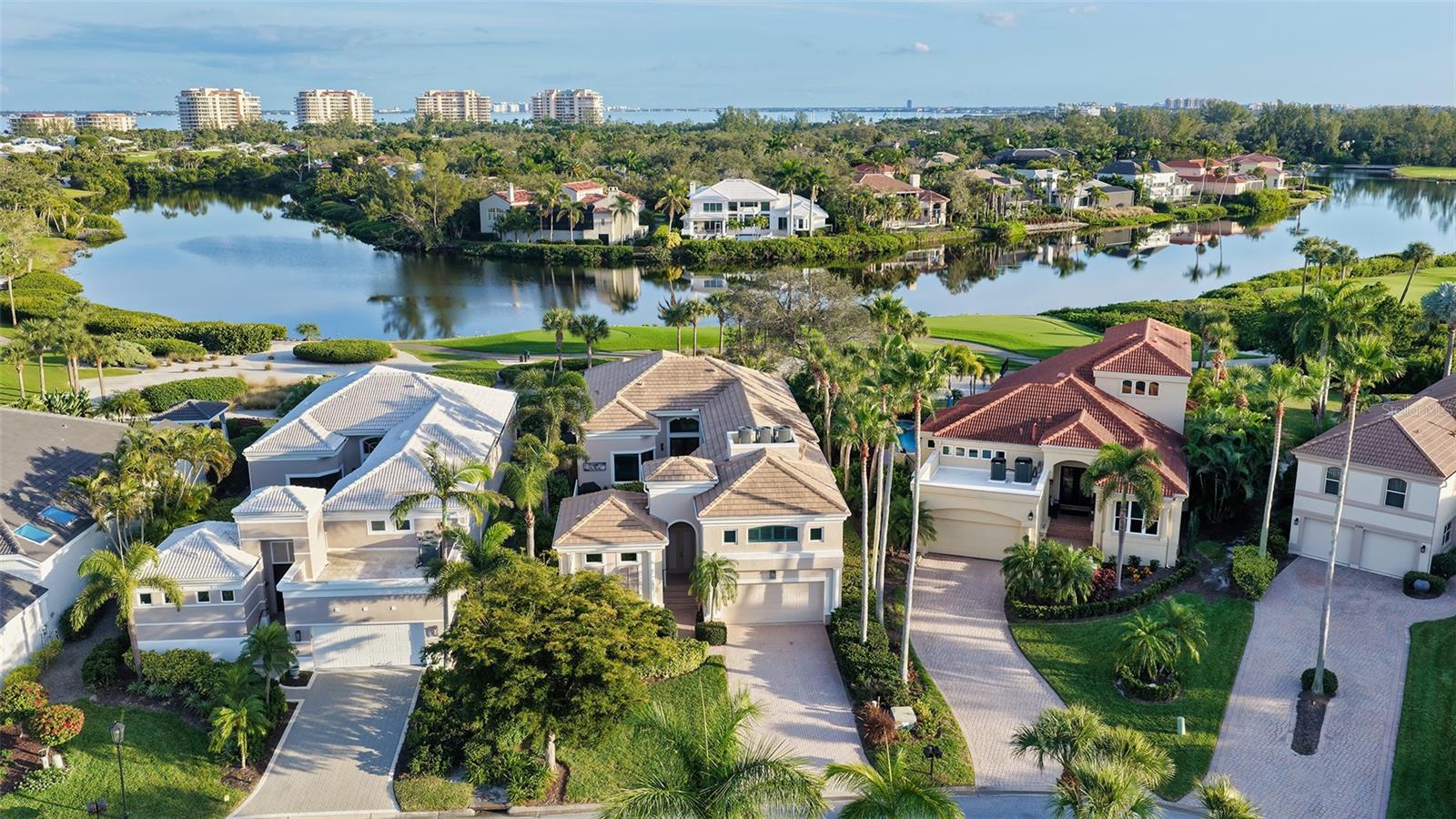 Situated within the gated Queens Harbour enclave of Bay Isles, this thoughtfully updated four-bedroom courtyard residence offers a refined blend of privacy, comfort, and waterfront living on Longboat Key. Designed around a lush central courtyard, the home creates an effortless indoor-outdoor flow anchored by a resurfaced swimming pool and new paver deck—an inviting retreat for everyday living or entertaining.

A private cabana suite with its own entrance provides flexibility for guests or extended stays, enhancing the home’s functionality while maintaining separation from the main living areas. Entry begins through custom mahogany and glass double doors, opening to a reimagined open-concept interior with soaring 14-foot ceilings, wide-plank wood flooring, and carefully curated architectural detail throughout.

The great room is centered around a travertine-encased electric fireplace and framed by walls of windows and glass sliders that capture tranquil lake views and abundant natural light. This space flows seamlessly into the formal dining area, highlighted by a statement chandelier and tongue-and-groove tray ceiling, and continues into the chef’s kitchen—designed as the heart of the home.

The kitchen features a dramatic 14-foot quartz-topped island, custom designer cabinetry by Sarasota Architectural Woodworking, and newer Thermador appliances, including a five-burner gas cooktop, dual built-in ovens, pull-out pantry cabinetry, and a 48-inch stainless sink. Adjacent informal dining and family spaces include aquarium-style glass windows and an oversized wet bar with a full-size wine cooler capable of storing over 100 bottles.

The primary suite, located on the main level, offers a peaceful lakefront setting with French-door access to the patio, custom built-in storage, and a walk-in closet. The spa-inspired bath was recently updated with dual quartz-topped walnut vanities, soaking tub, glass-and-stone shower, and private water closet. Also on the first floor are a versatile study overlooking the courtyard and a bonus room with an attached full bath that can serve as an additional bedroom or media space. The second level is dedicated to a private en-suite guest bedroom.

Queens Harbour residents enjoy access to a heated Olympic-size pool and spa, along with deeded entry to the private Bay Isles Beach Club. Beyond the gates, Longboat Key’s lifestyle amenities are just minutes away, including the Longboat Key Club’s golf and tennis facilities, marinas, dining, and everyday conveniences. St. Armands Circle and downtown Sarasota’s cultural attractions—shopping, galleries, theaters, and waterfront dining—are easily accessible, completing the appeal of this well-positioned coastal residence.
