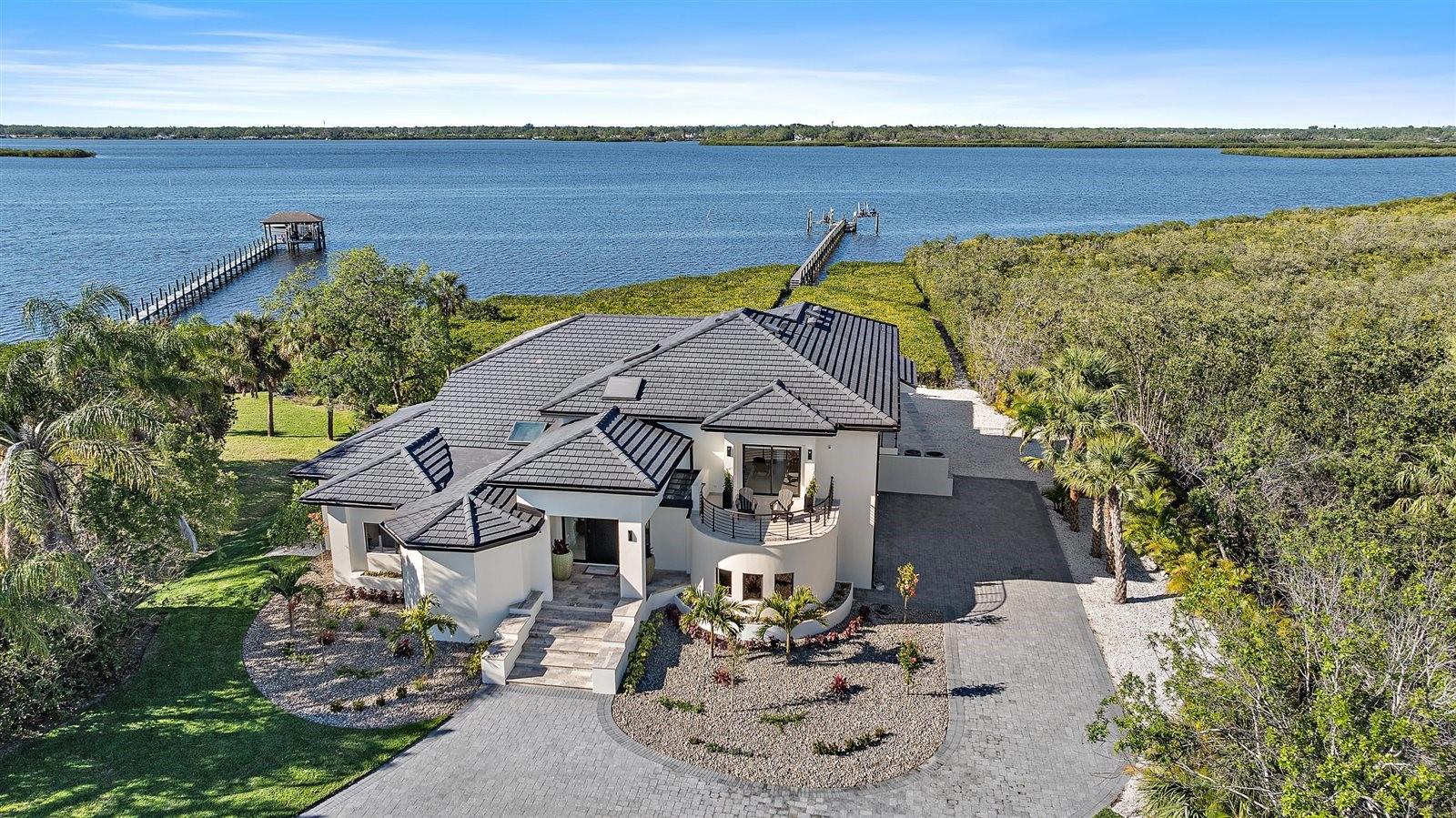 Ultra-Luxury Modern Waterfront Estate in Florida Step into a world of unparalleled luxury and serenity with this exquisitely reimagined waterfront estate, set on over 1.2 private acres. Designed by an internationally acclaimed architect, this masterpiece blends contemporary elegance with cutting-edge innovation, offering breathtaking water views and total privacy—with no neighbors to the east for over four miles. A grand 200+ foot circular driveway, newly paved and enveloped in $500,000 of lush landscaping and exterior upgrades, welcomes you to this hidden retreat. Hurricane-impact windows and a newly refinished concrete roof ensure both security and sleek modern aesthetics. House is very protected from hurricanes by the mangroves. During the last storms the house did not flood due to how the house is situated on the water. A Resort-Style Outdoor Oasis in a well maintained gated community! The completely transformed backyard is an entertainer’s dream. The refinished pool shimmers beside an extended floating sun deck, while a custom pergola with a motorized ceiling and retractable screening houses a high-end outdoor kitchen. A full bath and outdoor shower provides convenience, while a 10,000-pound boat lift accommodates vessels up to 28 feet. A private landing beach allows for effortless paddleboarding and kayaking, framed by manicured mangroves ensuring uninterrupted views. An Interior of Unmatched Elegance Inside, zero grout-line ceramic floors, soaring ceilings, and expansive hurricane-rated windows and sliders showcase sweeping water views. A custom-built, backlit feature wall, designed by master artisans, adds dramatic flair, while slimline AC vents and designer lighting enhance the modern aesthetic. The chef’s kitchen is a showstopper, boasting top-tier appliances, Italian cabinetry, and waterfall-edge quartz countertops. A hidden walk-in pantry with custom shelving elevates functionality. A Master Retreat of Pure Indulgence The primary suite has been reimagined as a private sanctuary, featuring an ultra-luxe spa-inspired bath with an oversized walk-in shower, custom his-and-hers closets, and LED-lit display cabinets for clothing, jewelry, and timepieces. Imported fixtures from across the globe complete this lavish retreat. A Bespoke Second Level Ascend the custom floating staircase, illuminated by soft LED lighting, to a serene balcony lounge overlooking the great room. Outfitted with built-in cabinetry and a coffee bar, it’s an idyllic space to unwind. All guest suites feature custom LED-lit closets and private balconies with stunning views. Reimagined for the Future Completely re-engineered, this estate boasts all-new electrical, plumbing, and HVAC systems, with raised ceilings and expanded square footage to enhance its grandeur. Never affected by storms, this home is as close to new construction as it gets—every inch meticulously curated for luxury, security, and modern elegance. This is Florida waterfront living at its absolute finest.