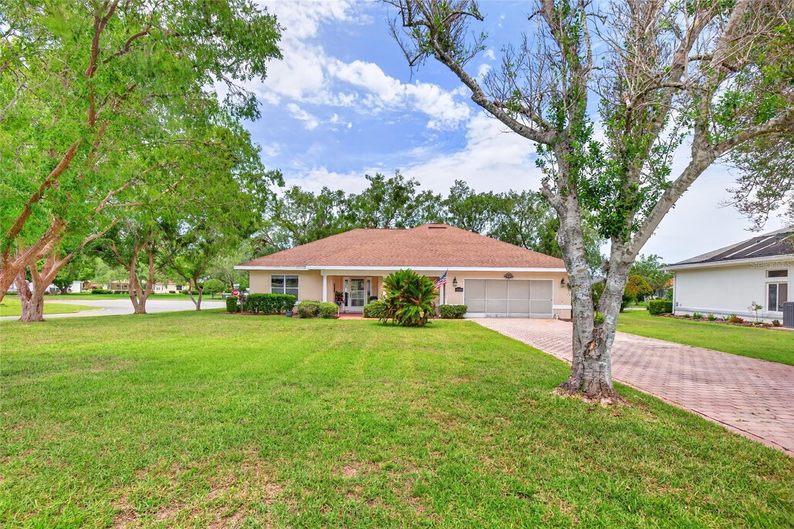 Virtually Staged. Gated, Stonecrest a 55+ community in Summerfield with the best of best amenities including pickleball, tennis, shuffleboard, softball, clubhouse, large pool with hot tub and more all overlooking the pond! 
Home sits on oversized corner lot with nice tree canvas and landscaping. The custom paver driveway leads to covered front entry and screened in 2 car garage. The welcoming front covered entry has room with for rockers or sitting area! Step through the storm door to tile foyer, living room straight ahead with quad sliders, to the left of foyer is the den/office/hobby room across from this room is the 2nd bedroom, leading to guest 2nd bathroom with walk in shower. spacious kitchen with 2022 sink, led lighting 2022, plenty of countertops and cabinet space. The laundry room sits in right of kitchen leading to large 2 car garage. As well as the primary bedroom, 3 built in closets for ample storage and primary bath with tub/shower combo. Stepping back through kitchen into oversized dining area with luxury vinyl plank and  double slider to enclosed and covered lanai. The living room with vaulted ceilings is in center of home and has quad sliders leading to the lanai as well with views of trees and no direct neighbors behind. Also a 10 x 10 patio for grilling or sunbathing patio. All carpet 2023, HVAC 2024, Roof 2004, all commodes upgraded to comfort level 2021,This golf cart community embraces all of the fun, needed amenities and relaxation the sunshine state has. Come to Stonecrest to live and call home! Just a stone throw to the villages!
