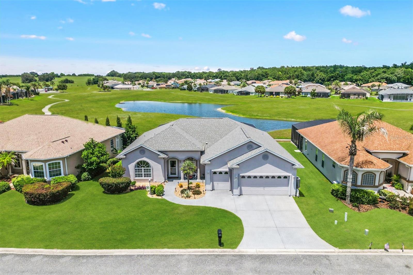 Virtually Staged. ~~NEW ROOF 2020, EXTERIOR PAINT 2021, NEW HVAC 2022,  NEW POOL 2024~~ Perfectly positioned on one of STONECREST's serene interior lakes, this exceptional 3 Bedroom, 3 Bath with 2 car plus GOLF CART Garage with electric screen door residence captures everything someone dreams about when they imagine living in Central Florida. SPLIT BEDROOM Floor plan offers 2 spacious en-suite bedrooms, creating privacy and comfort for family and overnight guests alike. Soaring 10' ceilings, an abundance of natural light, and an OPEN FLOOR PLAN create an inviting atmosphere where nearly every room across the back of the home enjoys uninterrupted views of the sparkling pool and tranquil lake. A private DEN with French doors provides the perfect space for a home office, reading room, or creative retreat.  The true centerpiece of this home is the OUTDOOR LIVING Experience. Beneath an impressive 26' x 56' SCREENED ENCLOSURE/birdcage, the newly completed electric heated SALTWATER POOL offers a resort inspired escape with a cascading waterfall and an expansive SUN SHELF designed for lounging in just a few inches of refreshing water. DOUBLE SLIDING GLASS DOORS in Living room, opening to a COVERED LANAI complete with a mounted television, refrigerator, and direct access to the 3rd FULL BATH. ~~NEW ROOF 2020, EXTERIOR PAINT 2021, NEW HVAC 2022, POOL 2024.  TILE and LAMINATE Flooring flow throughout the home, complemented by a WHOLE HOUSE WATER SOFTENER SYSTEM,  VACUUM SYSTEM FOR GARAGE~~ and a spacious indoor laundry room.  This sought after Gated 55+ Golf Community offers an active, welcoming lifestyle where neighbors quickly become friends. Even better, you can leave your car parked and travel by golf cart to nearby shopping, restaurants, medical facilities, and everyday conveniences.  It's a lifestyle that's becoming increasingly rare, a place where errands become enjoyable outings, evenings are spent with friends, and every day carries the relaxed rhythm of a permanent vacation. This isn't simply another Florida pool home. It's the place where mornings begin with peaceful lake views, afternoons are spent poolside, and every sunset reminds you that you've finally found the lifestyle you've been waiting for. WELCOME HOME to your own piece of paradise!  (Furniture available.)