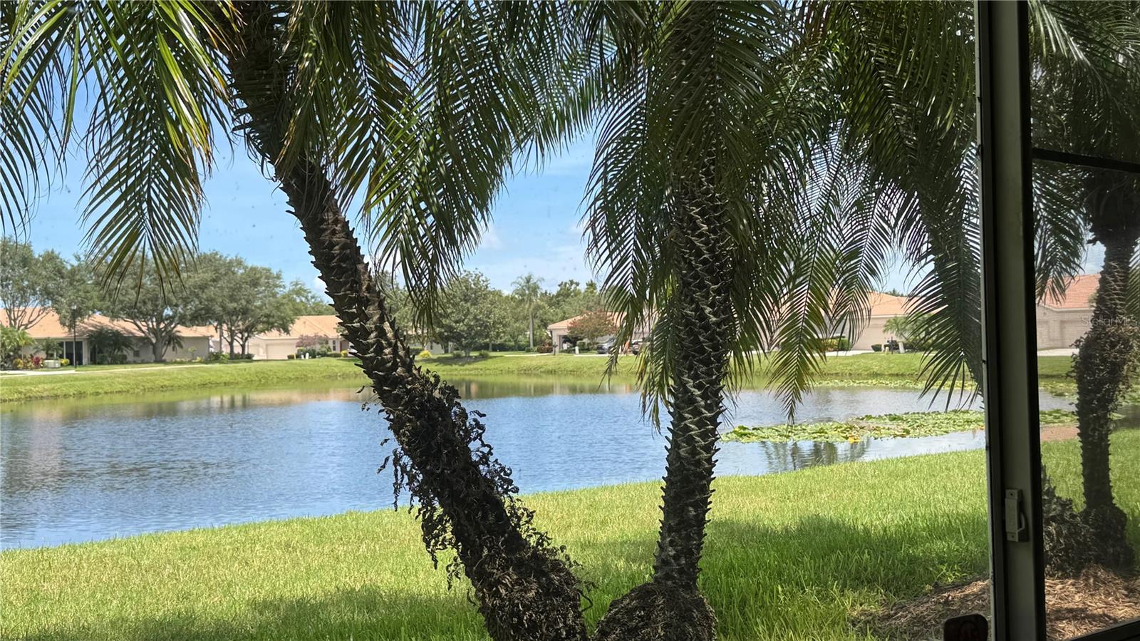 HUGE PRICE REDUCTION! Welcome to your dream home in the serene, gated 55+ community of Lakeridge Falls! This end unit villa perfectly blends comfort, elegance, and low-maintenance living, making it ideal for your next chapter. The updated kitchen features upgraded wood cabinets with soft close doors and drawers. Plenty of cabinet space, granite countertops and Italian porcelain floor tile. New refrigerator. Natural gas range. Open concept living, high ceilings, newly installed Bruce engineered hardwood flooring throughout great room and spacious den, creating a bright atmosphere.  Since villa is on the end it allows extra windows for extra light. Brand new washer/dryer in dedicated laundry room. New gas water heater (2026). Split bedroom design. Home features spacious primary bedroom with newly installed carpet. Primary bath has new upgraded wood cabinets with soft close doors. Primary bath has dual sinks and walk-in shower. Primary bedroom has two closets, one being a large walk-in closet.  Good size guest bedroom has new carpet, nearby bath with tub/shower combination, with new vanity and tile. Perfect place for working from home since den has solid double doors. Attached two car garage. Spacious enclosed lanai giving pleasant daytime and evening lake views and stunning sunset views. Newly remodeled and updated clubhouse with a heated pool, spa/hot tub, fitness center, community room, bocce ball, card room, yoga, and water aerobics. Active social calendar with many events and outings to choose from. Miles of walking/biking trails, lush landscaping, and pet-friendly sidewalks. 24-hour manned guard gate and excellent community management. HOA covers lawn maintenance, landscaping, lakes and sidewalks for stress-free living. Convenient location close to shopping, Publix, Walmart, Panera, Detweillers, Starbucks, dining, medical facilities, and the UTC Mall. Short drive to I-75, downtown Sarasota, Bradenton, SRQ airport, Lido Key, Siesta Key, and Anna Maria Island. Home is ready to add your own choice of interior paint colors. Come and enjoy the peaceful, active lifestyle you deserve!