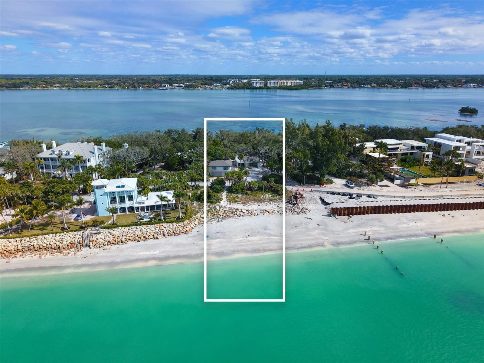 On the quiet and coveted stretch of North Casey Key, where century-old oaks meet the shoreline, and the land unfolds uninterrupted from Gulf to bay, this extraordinary 1.5-acre estate offers a rare opportunity to steward one of the island’s most incredible homesites. With 180 feet of private Gulf frontage and exceptional depth across to the intercoastal, the property is defined by its scale, privacy, and quiet permanence—offering a setting that feels both expansive and deeply secluded beneath a canopy of mature coastal forest. Here, the rhythm of the water and the natural beauty of the land create an environment that cannot be replicated. The existing improvements include a Gulf-facing main residence, originally constructed in the early 1970s, thoughtfully positioned to capture sweeping views in both directions. The two-bedroom, two-bath home features elevated ceilings, expansive windows, and a sunlit central courtyard designed to bring light and the surrounding landscape into everyday living. A separate guest house, completed in 2002, provides two additional bedrooms and baths, bamboo flooring, Bahama shutters, a versatile bonus room, and an oversized two-car garage—offering flexible accommodations for guests, or interim use while renovating or building. A recently installed private dock completes the property’s rare Gulf-to-Bay lifestyle and provides immediate access to boating and waterfront recreation. While the existing structures offer renovation potential and immediate livability, the true and enduring value lies in the land itself. Homesites of this magnitude—spanning Gulf to bay with this level of frontage, privacy, and natural beauty—are rarely available. Conceptual plans by Potter Homes envision a timeless coastal estate exceeding 6,500 square feet under air, thoughtfully designed to preserve the character of the land while capturing panoramic water views and creating a residence of lasting architectural significance.
Whether preserved, renovated, or reimagined entirely, this is more than a homesite—it is the foundation for one of Casey Key’s next great estates, and an opportunity to create something that will endure for generations.